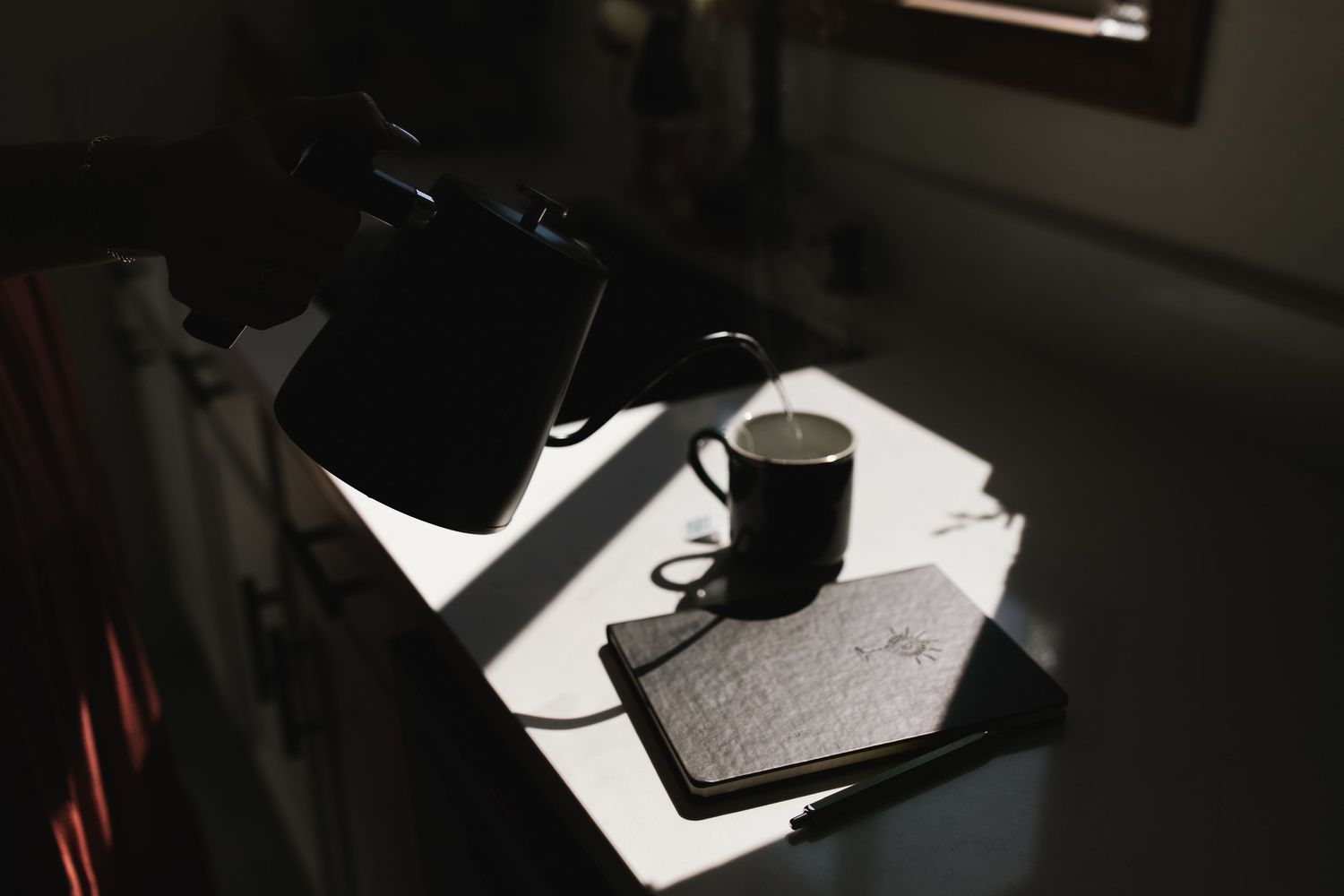 A black object casting dramatic shadows on a white surface in moody lighting.