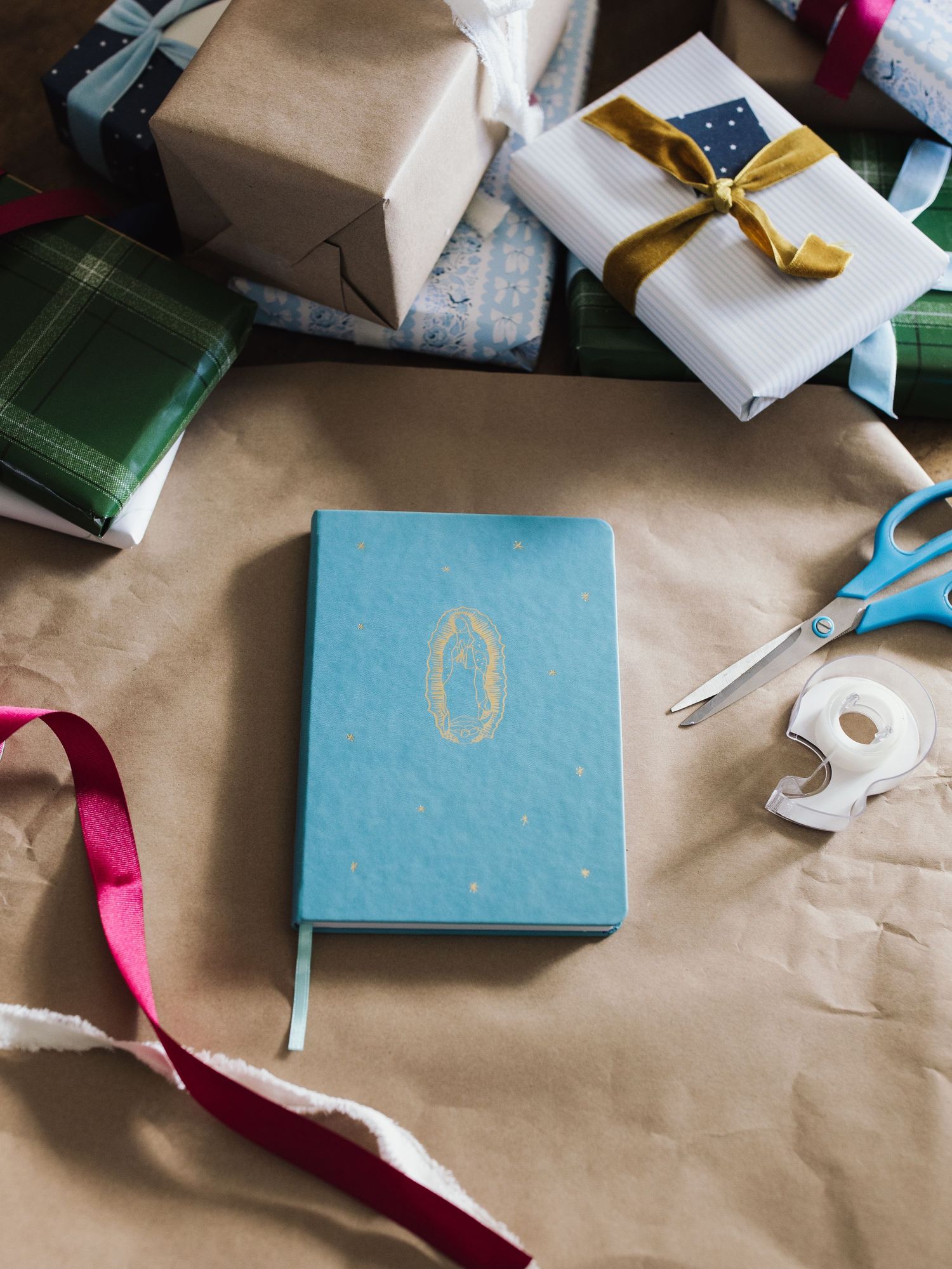 Kraft paper wrapped gifts with colorful ribbons and a light blue book or card displayed in sequence.