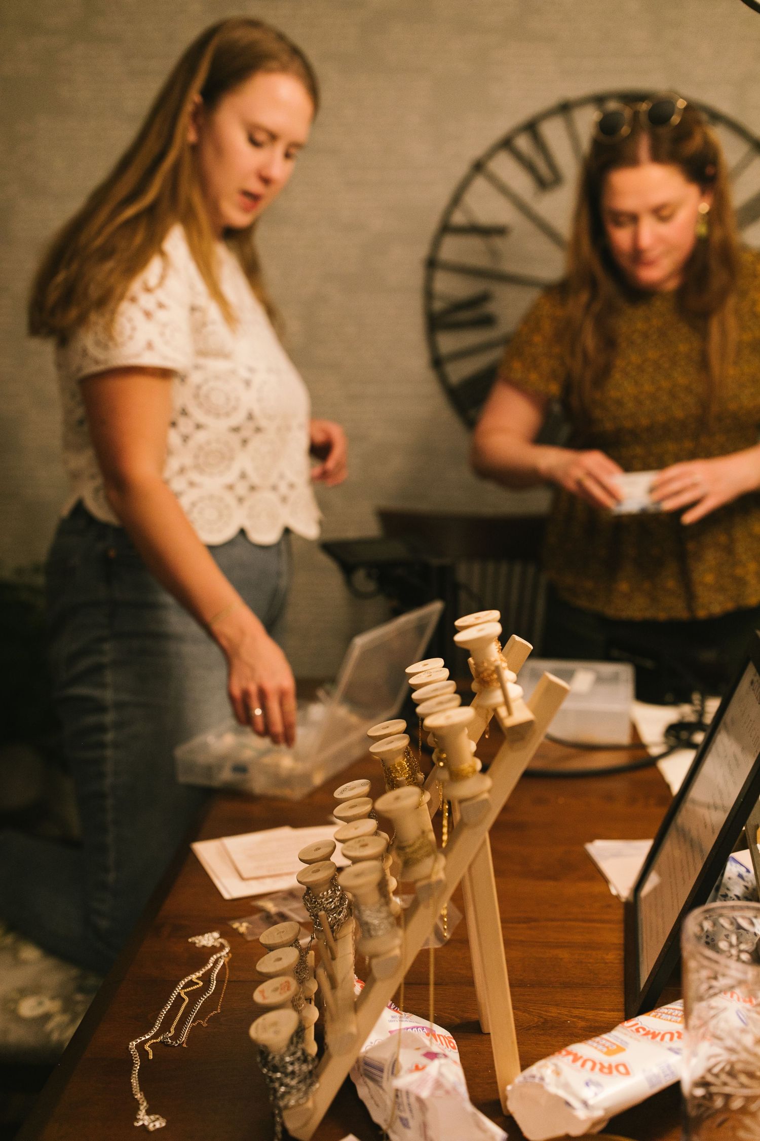Crafting supplies and wooden spools displayed on a work table with a clock in the background.