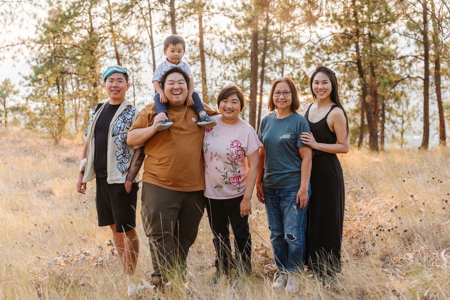 Group of people posing together in a scenic wooded area during golden hour.
