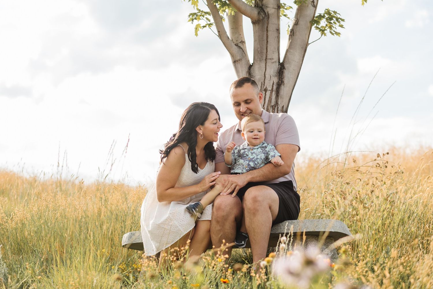 Family enjoying a tender moment together in a sunlit meadow during golden hour.