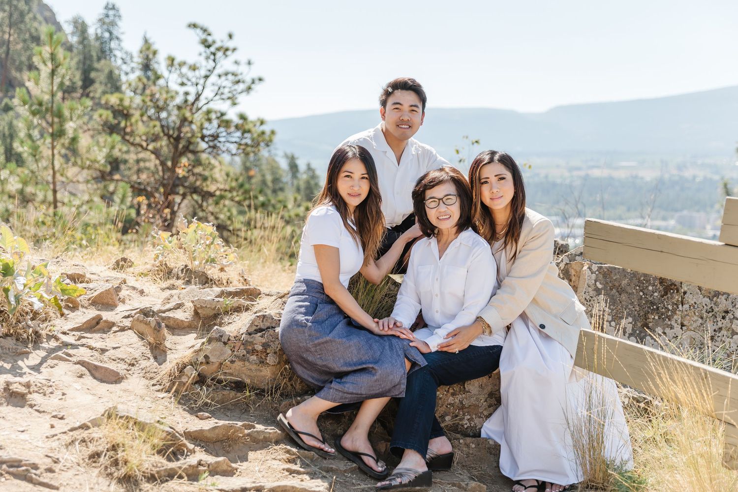 A family wearing white outfits poses together on a scenic mountain overlook during golden hour.
