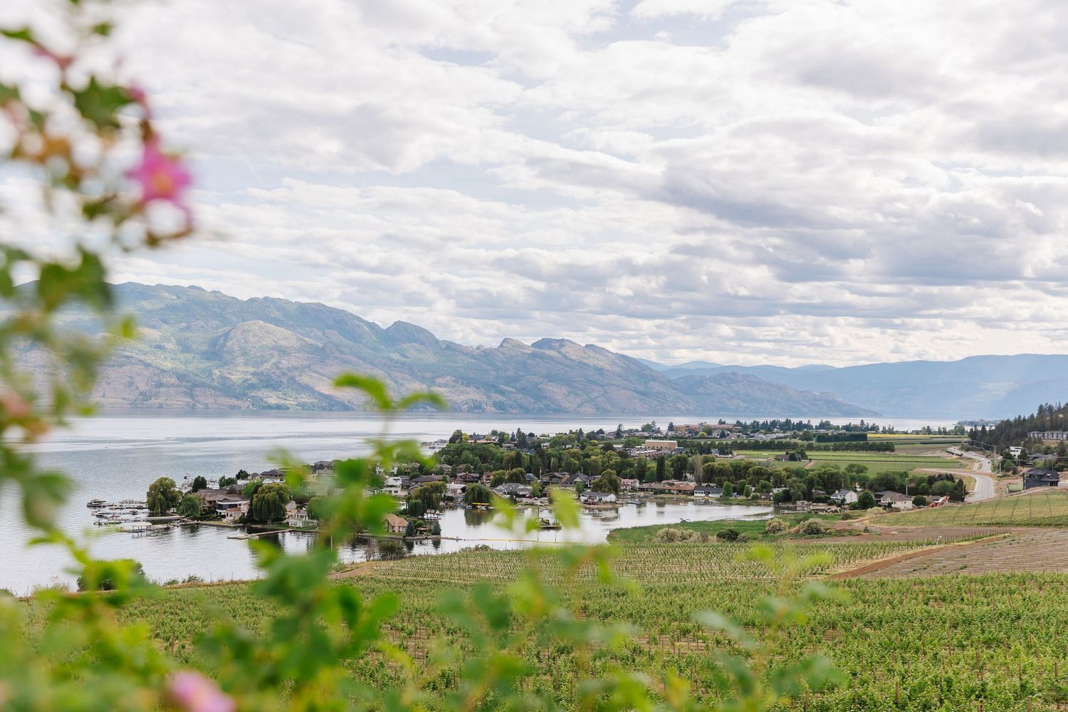 Panoramic view of a mountain landscape with green fields and scattered buildings under cloudy skies.