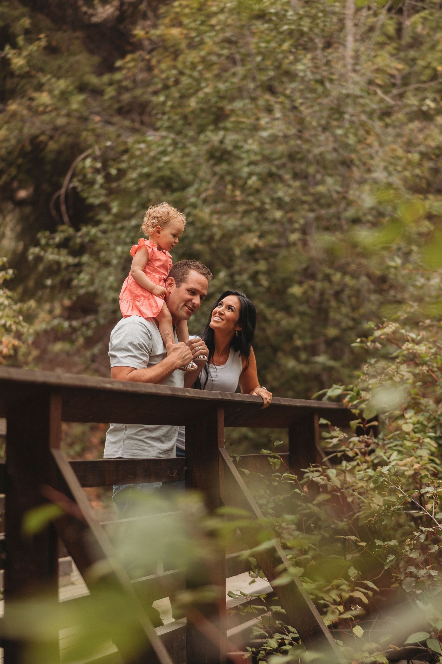 A happy family shares a tender moment together while sitting on a wooden bench surrounded by lush greenery.