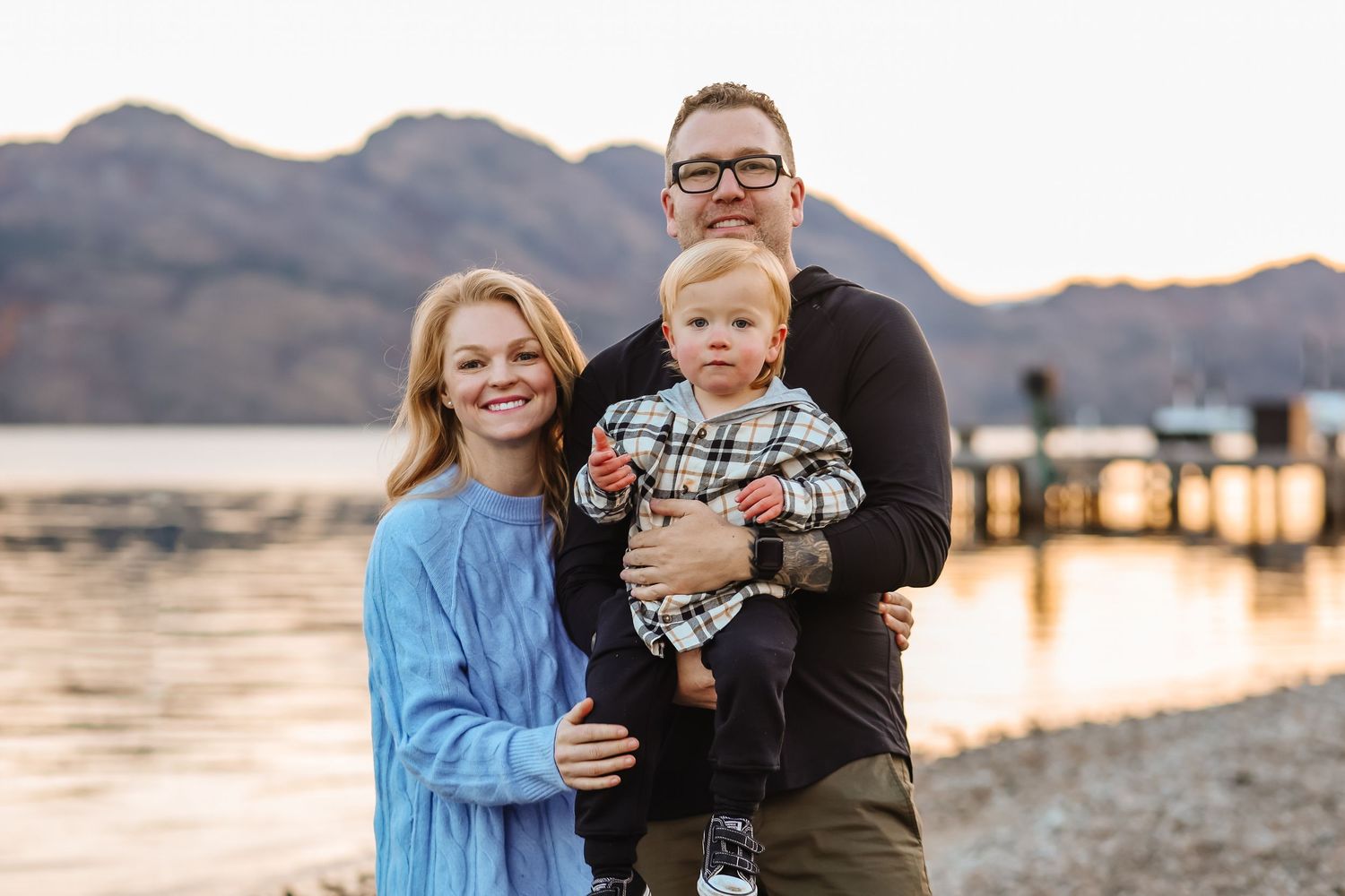 A family poses together in an outdoor desert landscape setting during golden hour.