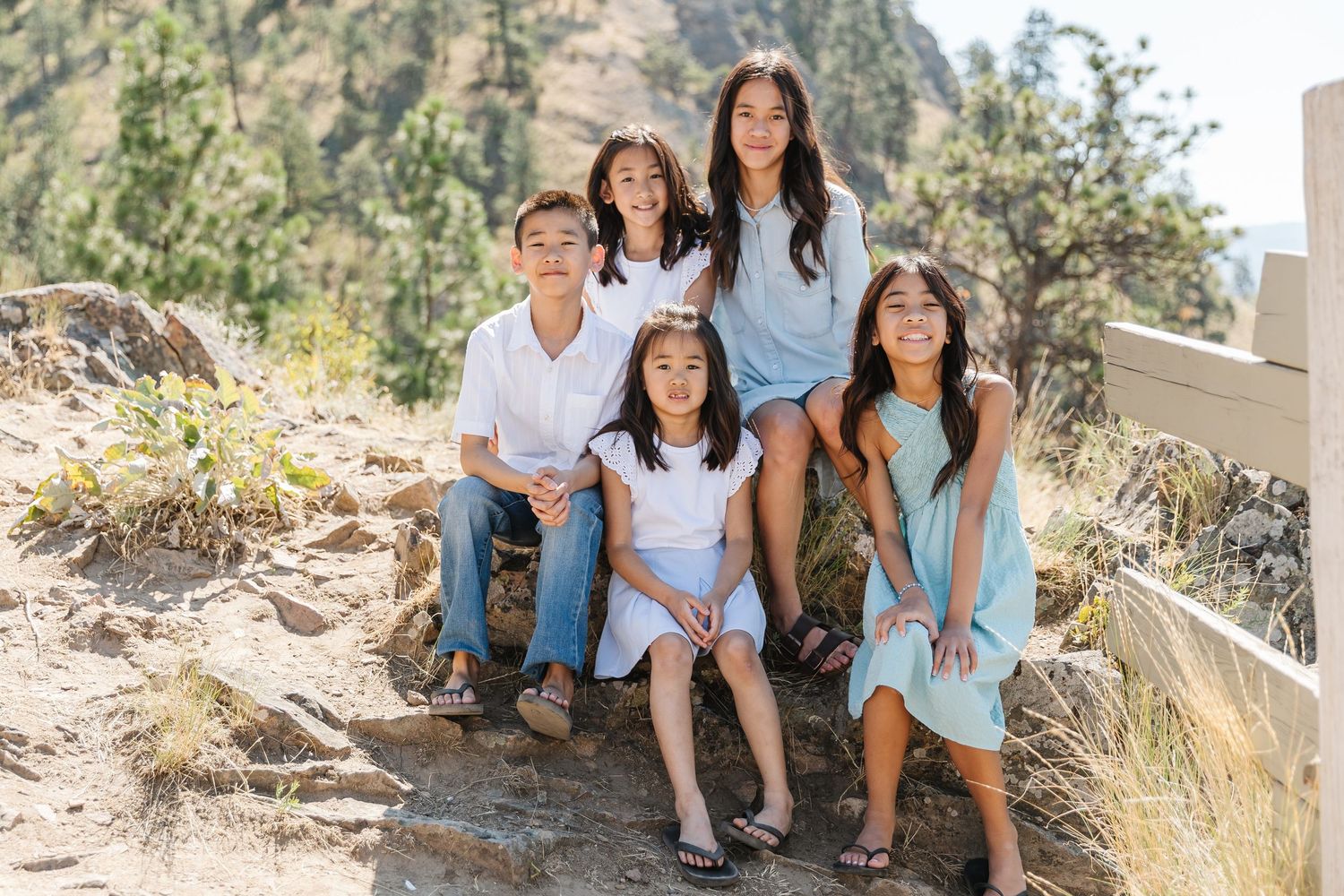 A group sits together on stone steps in a sunny outdoor setting wearing coordinated blue and white outfits.