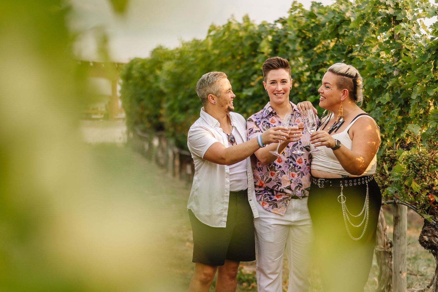 Group enjoying wine tasting and conversation in scenic vineyard on sunny afternoon.