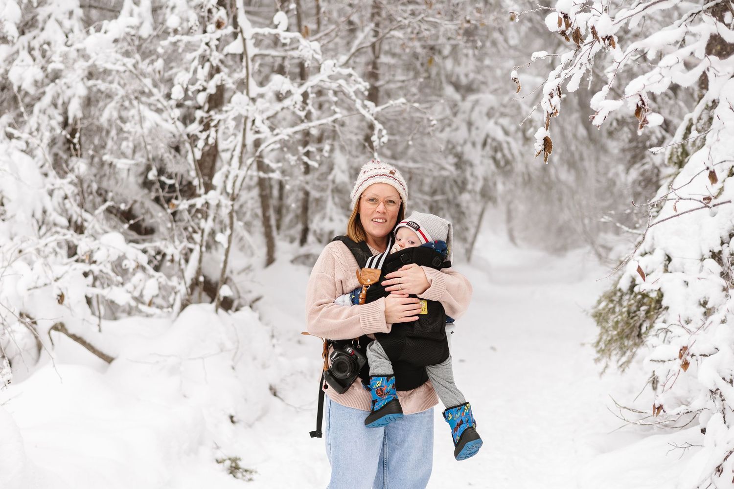 A snowy winter engagement photoshoot shows a couple embracing in a serene forest landscape.
