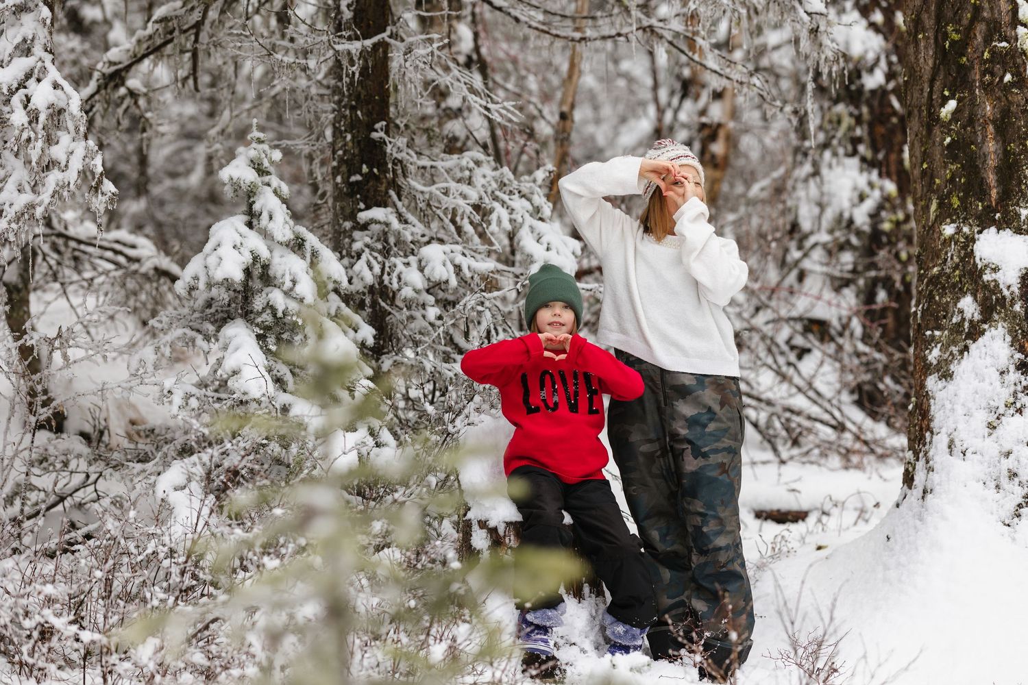A couple plays together in the snowy winter forest while throwing snowballs and enjoying the frosty weather.