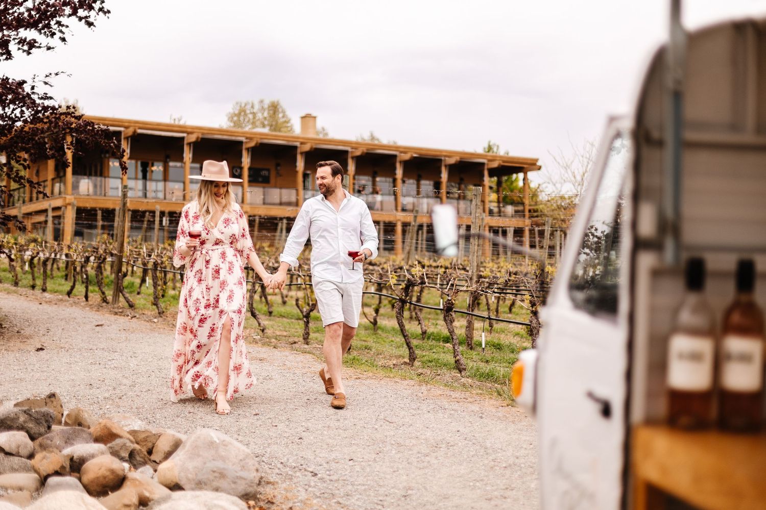Romantic couple walking together through a rustic vineyard setting during golden hour.