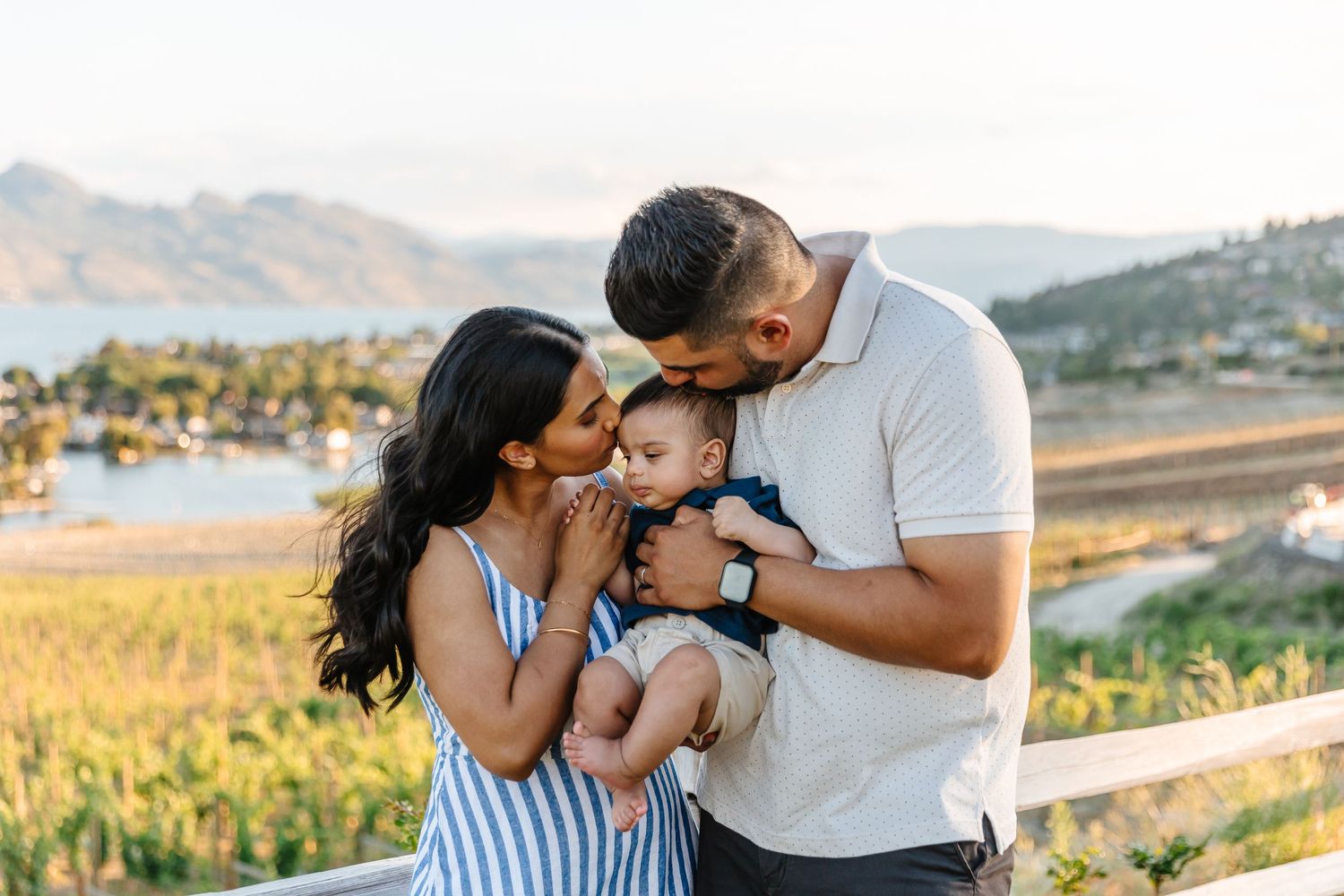 A couple embraces in a romantic moment against a scenic mountain vineyard landscape at sunset.