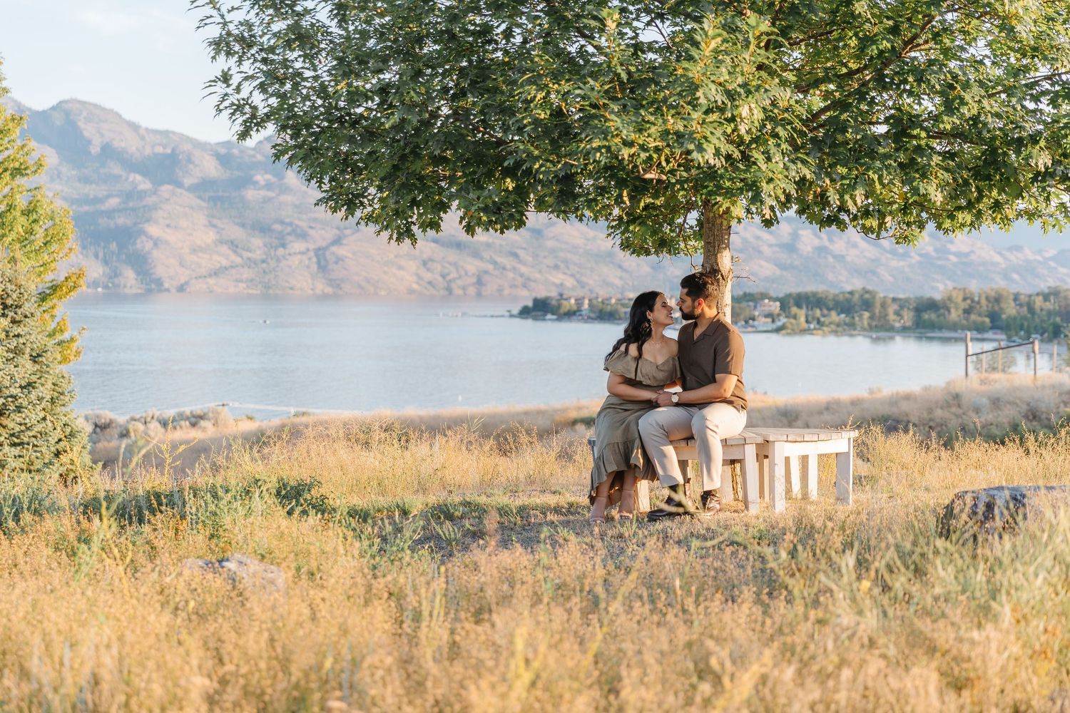 Romantic couple enjoying a picturesque sunset view from a scenic overlook in the mountains near a tranquil lake.