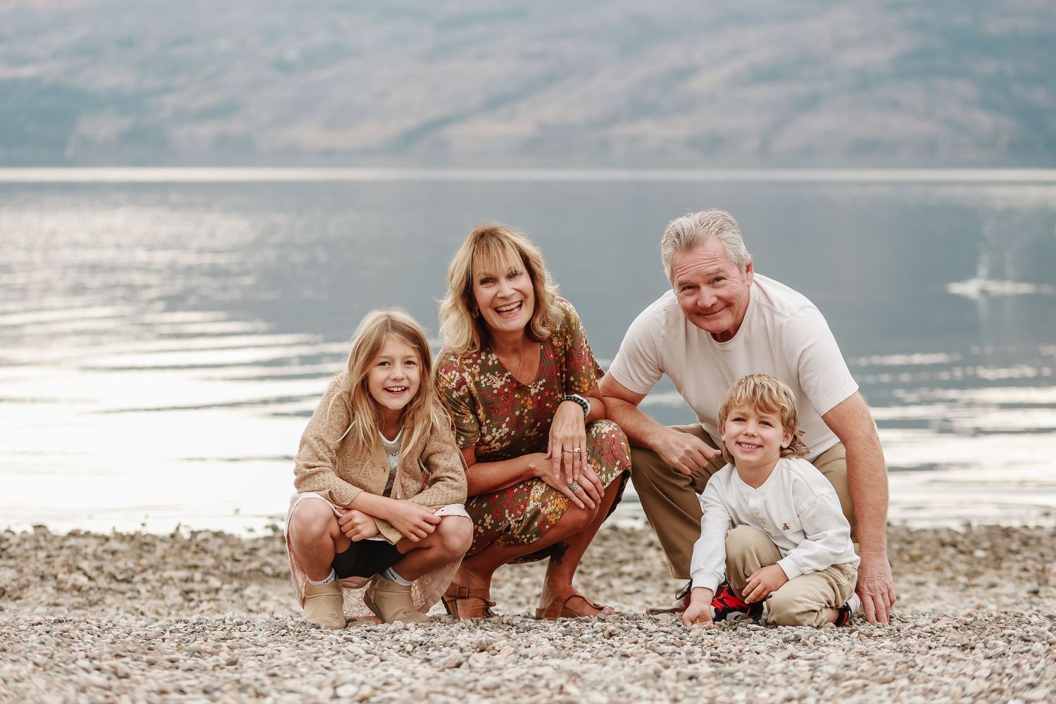 Family lying together on a beach shoreline during a photo session at sunset.