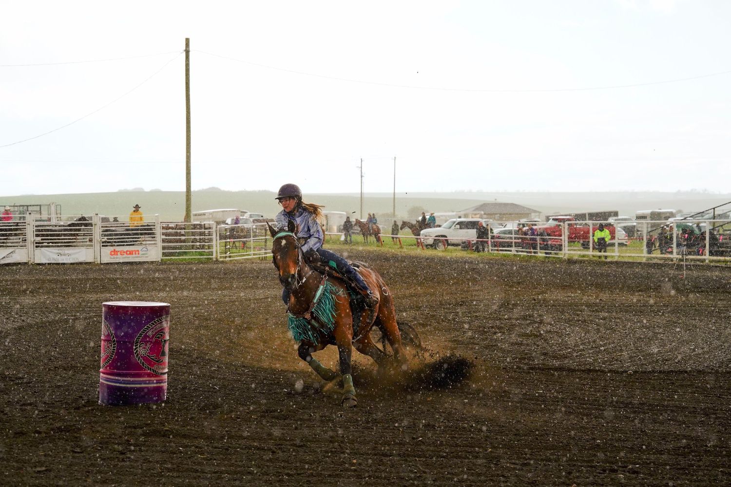 Rodeo riders compete in a series of barrel racing events on a dirt arena track.