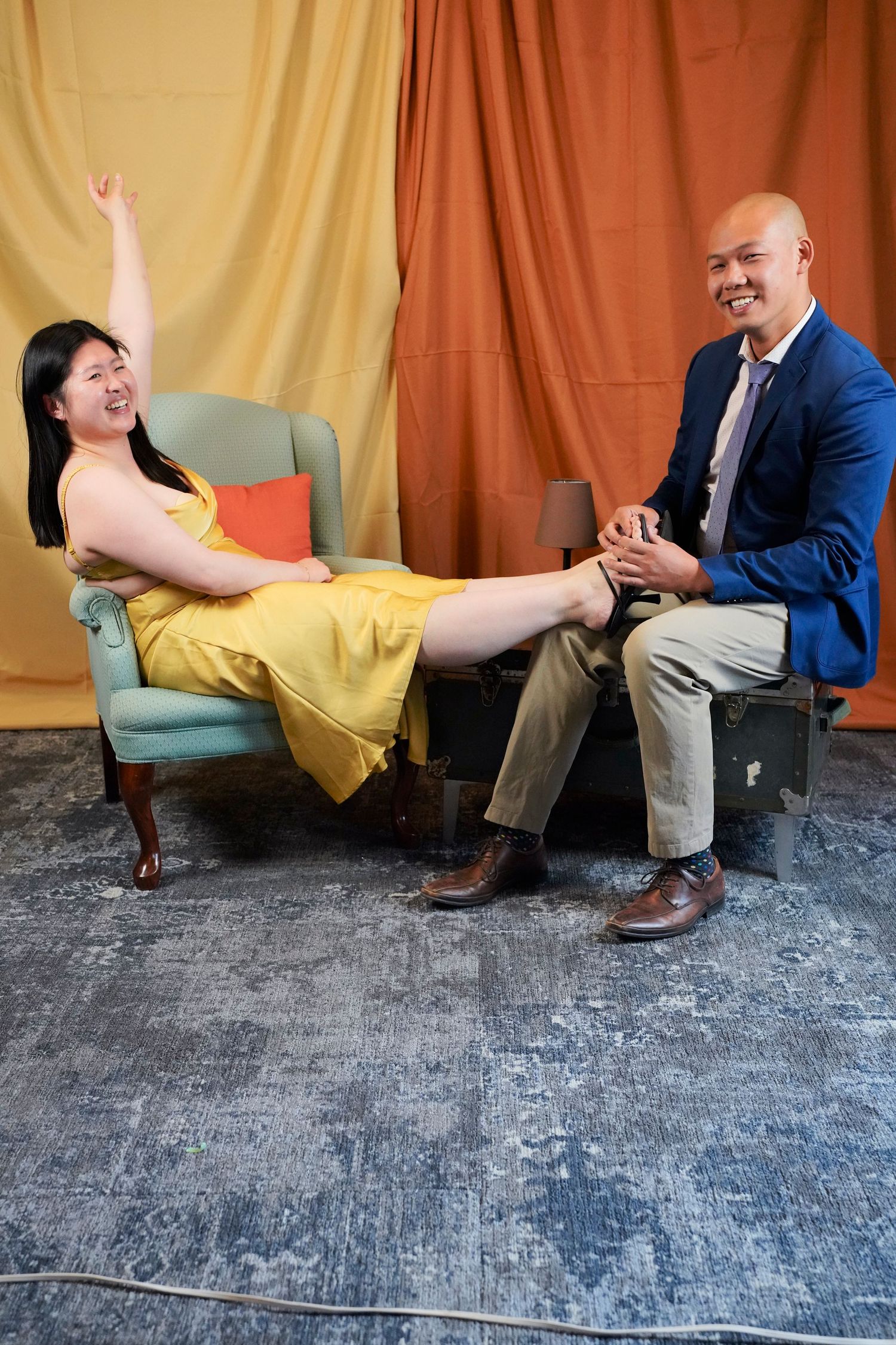 Multiple frames show two people sitting and interacting playfully with simple movements against a cloth backdrop.