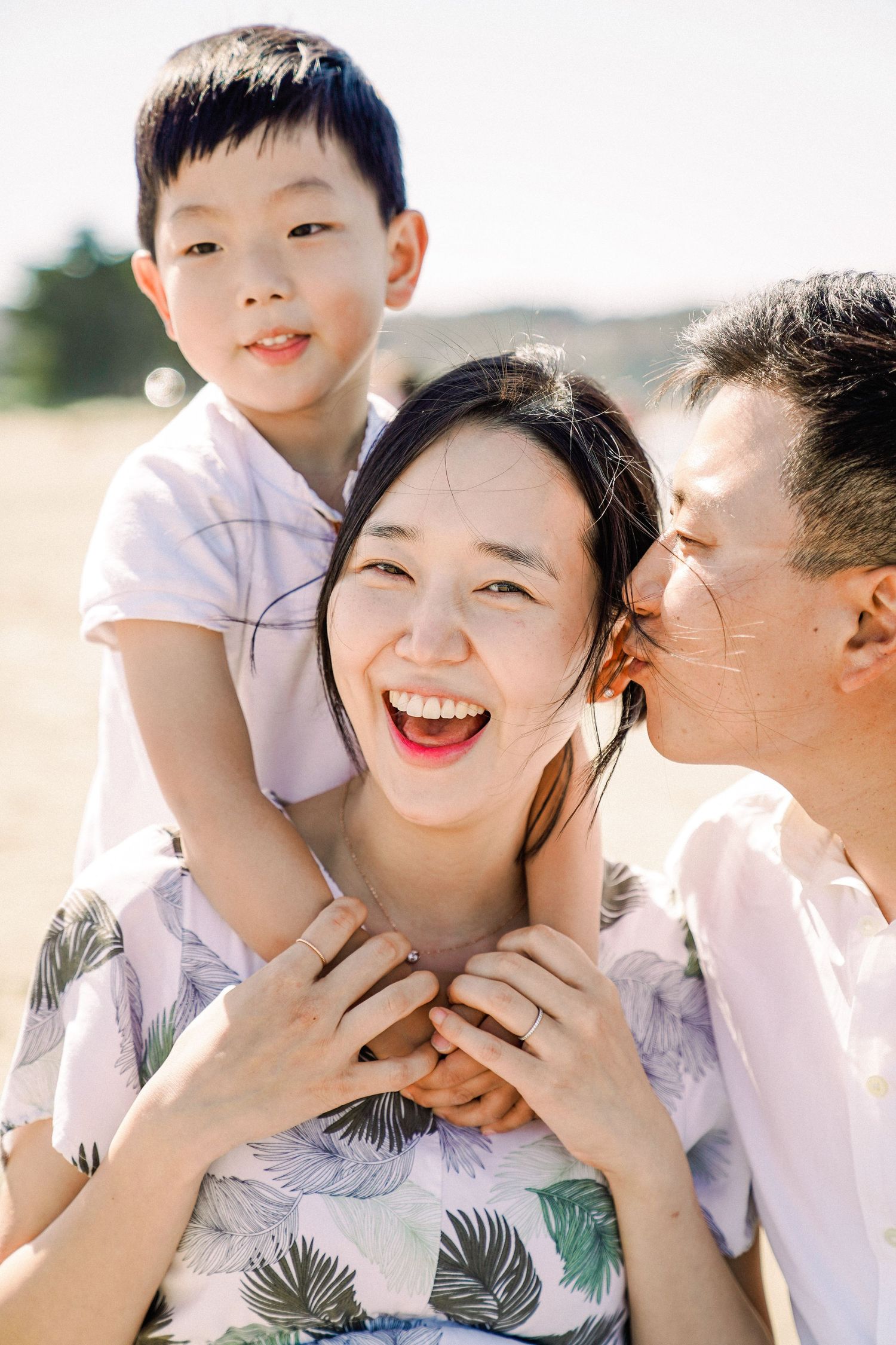 Family wearing white and pastel colors share joyful moments and laughter together in a series of candid photos outdoors.