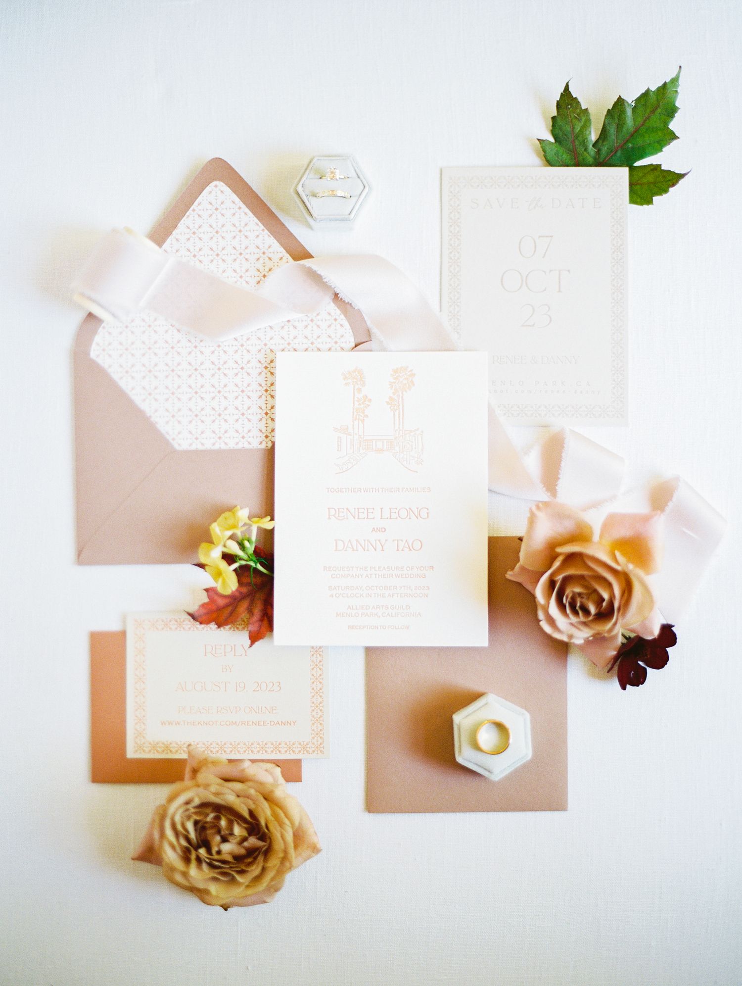 Elegant wedding invitation suite in blush tones with roses and hexagonal details laid on white background.