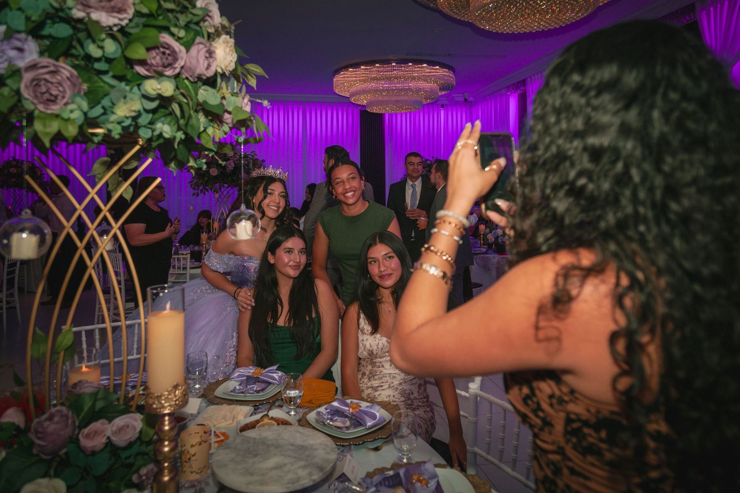 People enjoying a festive celebration with purple lighting and decorative elements in an indoor venue.
