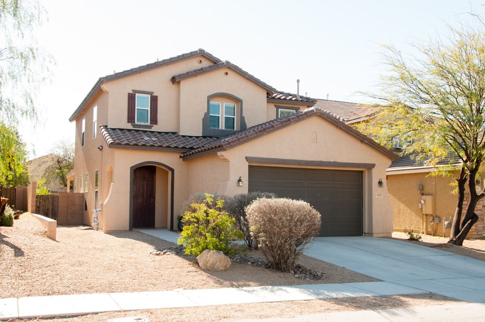 Modern beige stucco house with desert landscaping and attached garage in a southwestern residential neighborhood.