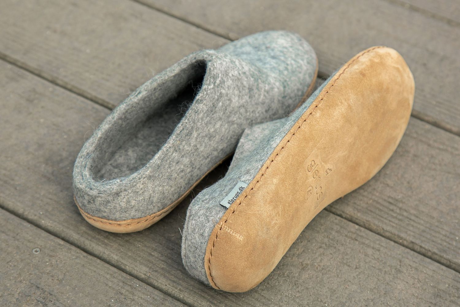 Gray and tan leather tabi boots shown from different angles on wooden deck surface.