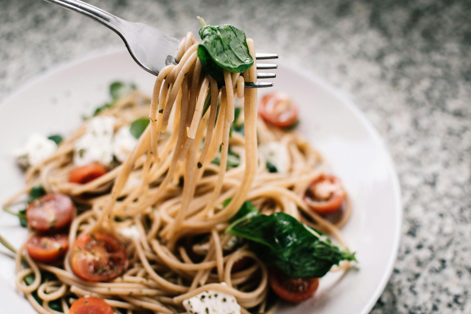 Steaming hot shrimp linguine pasta with fresh herbs and garlic being tossed in a pan.