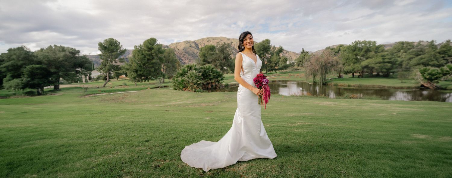A wedding couple poses in a scenic outdoor setting with mountains, golf course greens and natural landscapes.