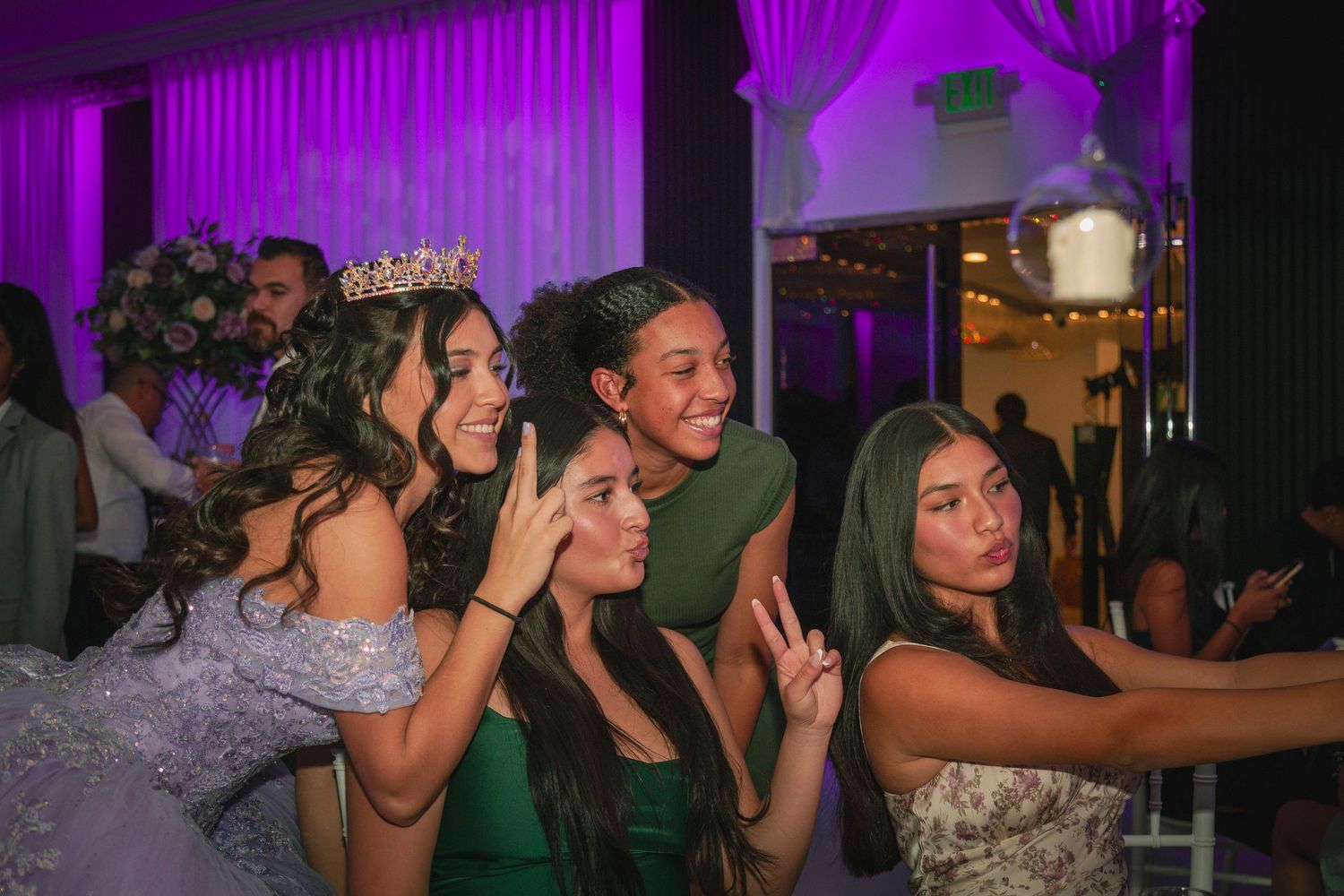 People dancing and socializing in a nightclub with purple lighting and a crowded dance floor atmosphere.
