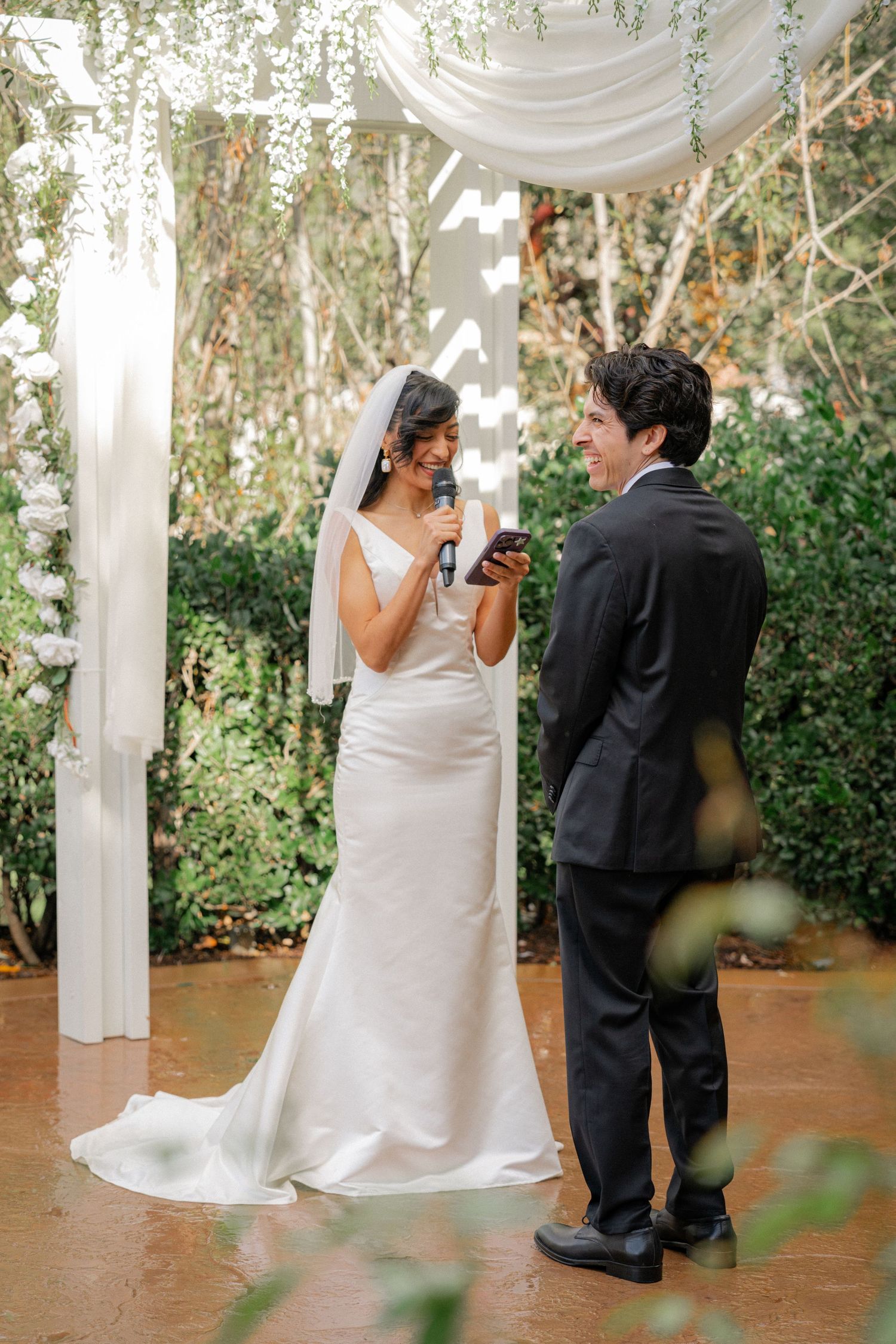 A romantic wedding moment captured in a series of photos showing a couple dancing under white draped fabric and greenery.
