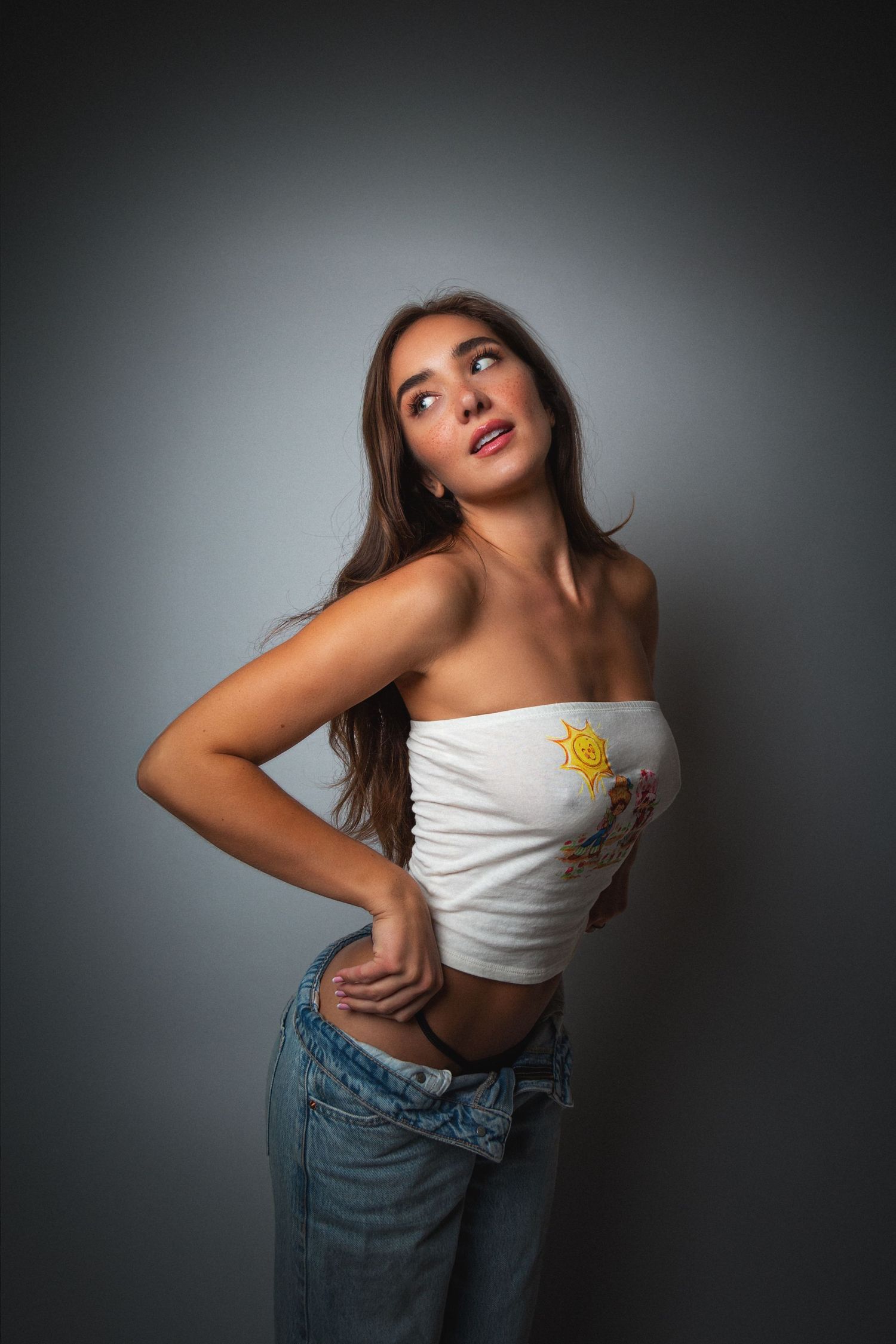 A series of dynamic fashion poses featuring a white crop top and denim jeans against a dark studio backdrop.
