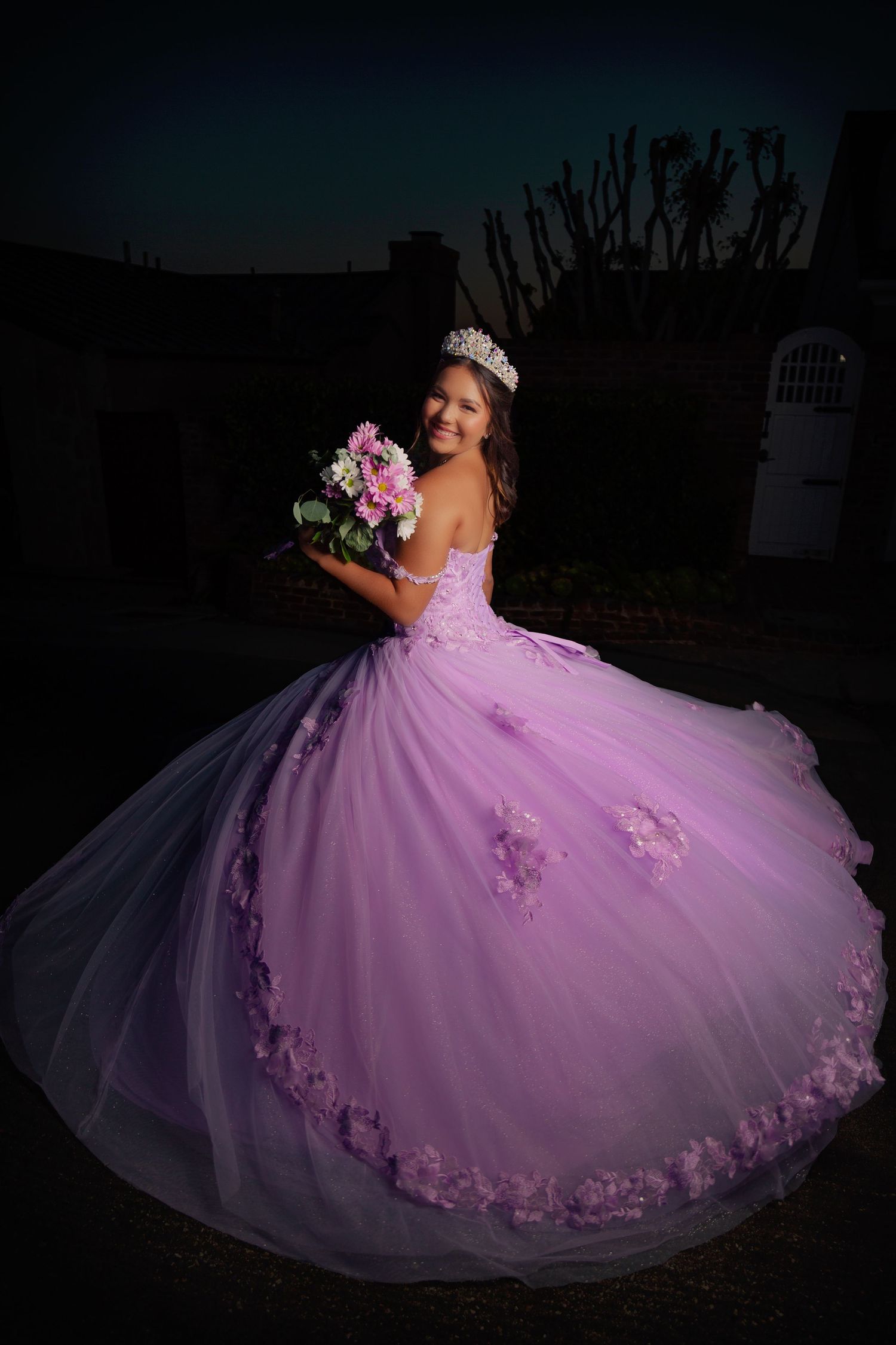 A stunning lavender quinceañera dress with floral appliques photographed during sunset in multiple angles.