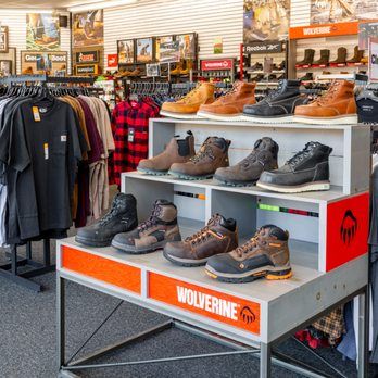 Display of rugged work boots and outdoor footwear on retail shelving with Wolverine brand signage in a shoe store.