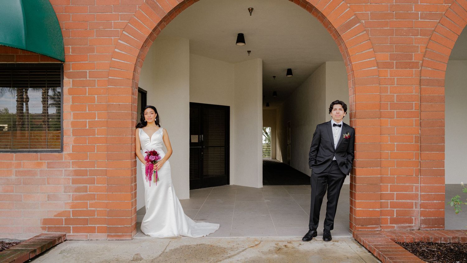 A panoramic view of a brick hallway with a couple in wedding attire standing at various positions.