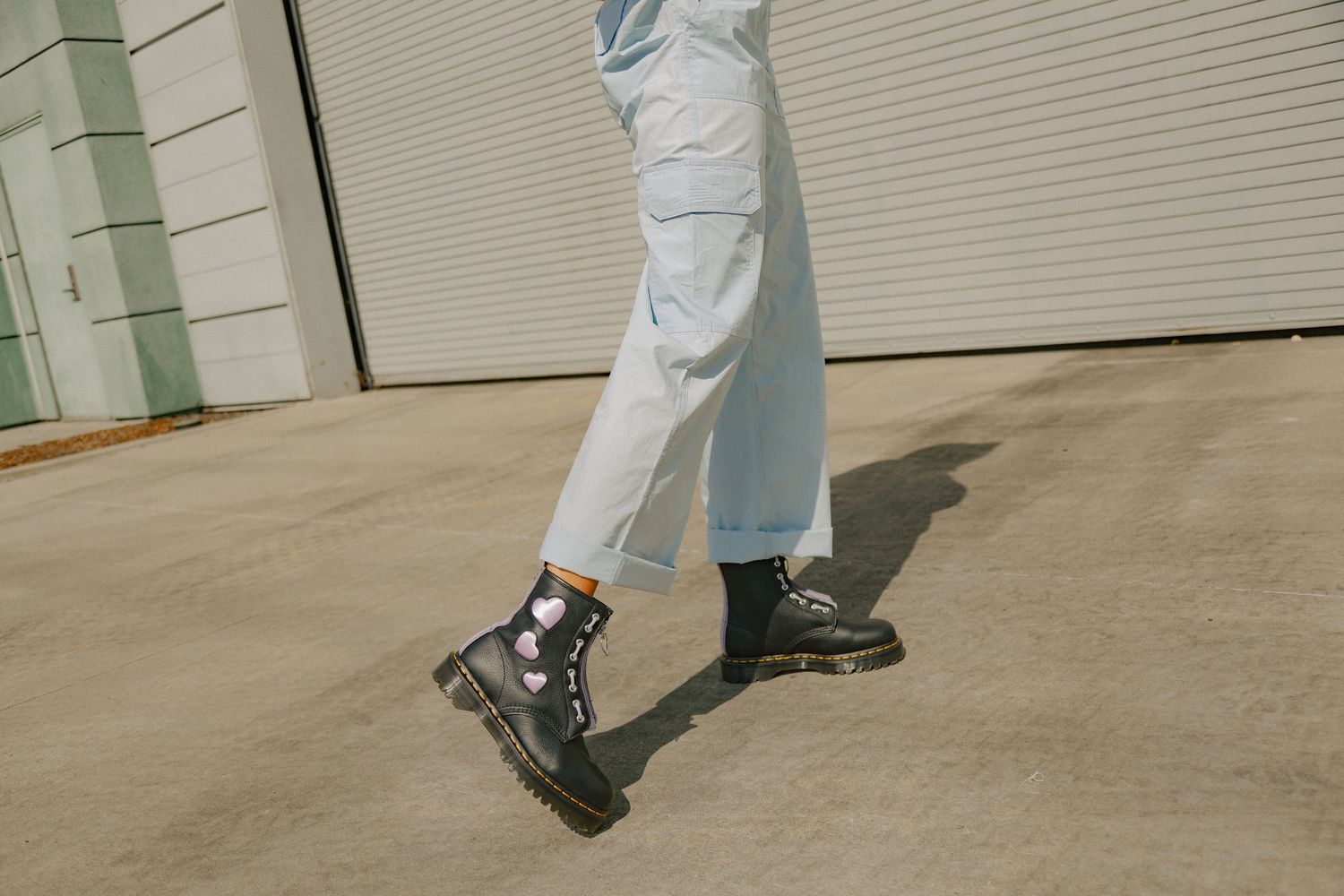 Person in light colored clothing and dark shoes walking across a beige tiled floor in a commercial space.