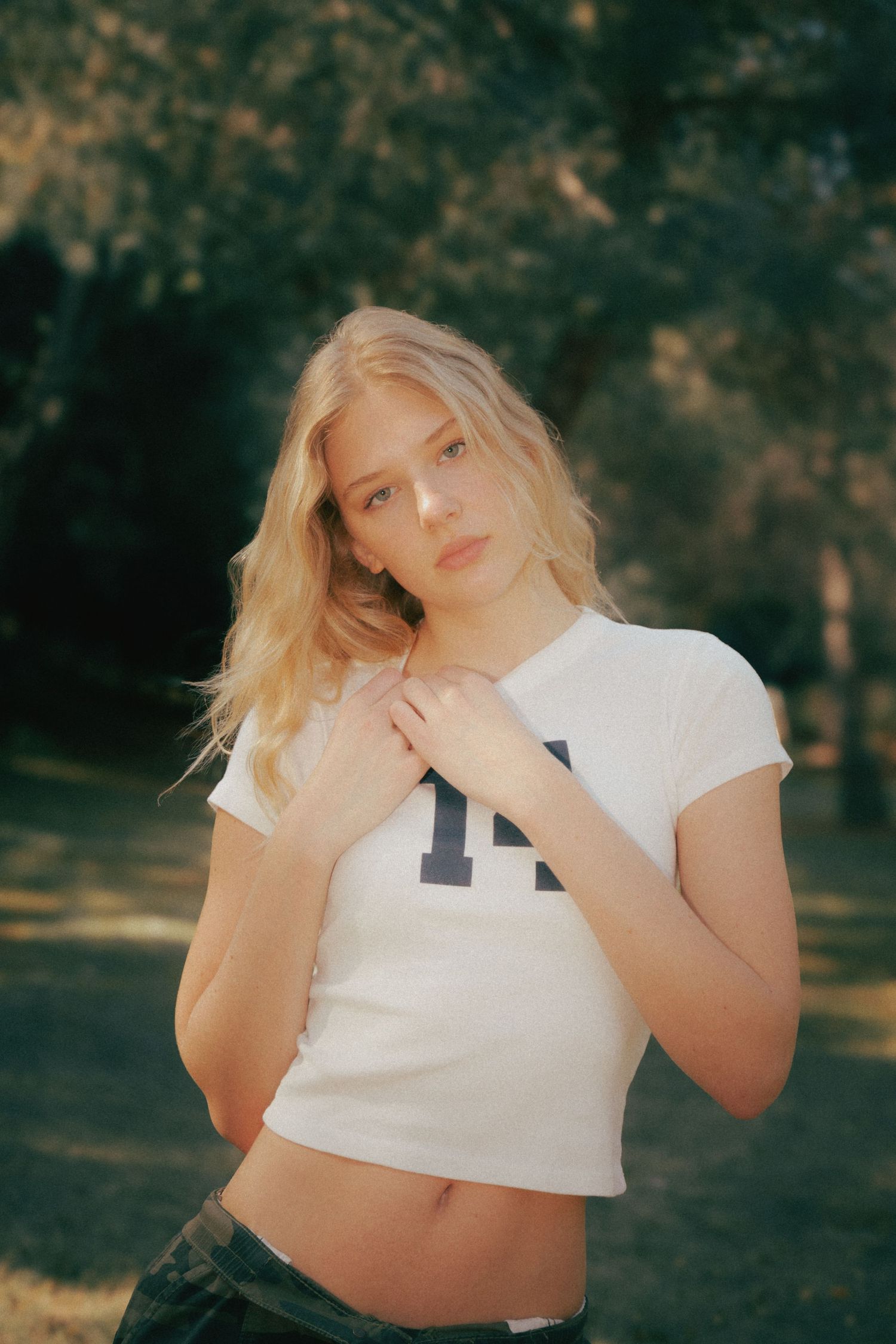 A series of artistic outdoor portraits showing someone in a white crop top against a moody natural background.