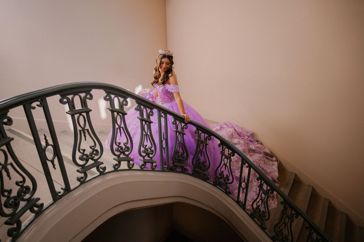 Ornate wrought iron staircase railing curves elegantly with purple lighting effects in a dimly lit interior space.