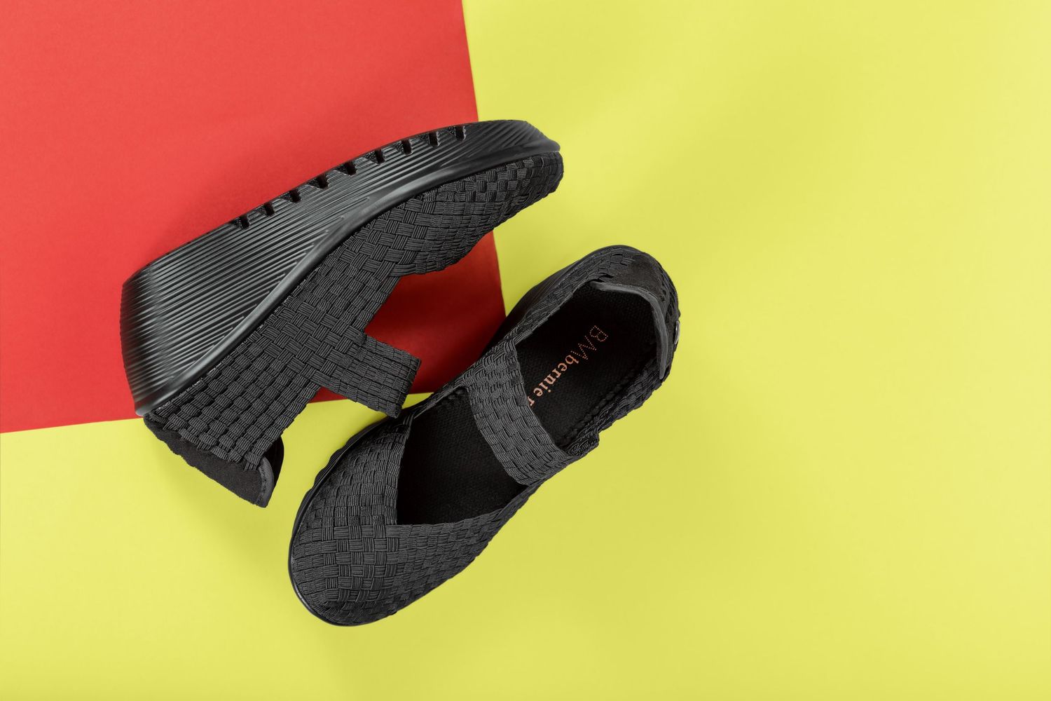 A pair of black athletic sneakers shown from different angles against red and yellow backgrounds.
