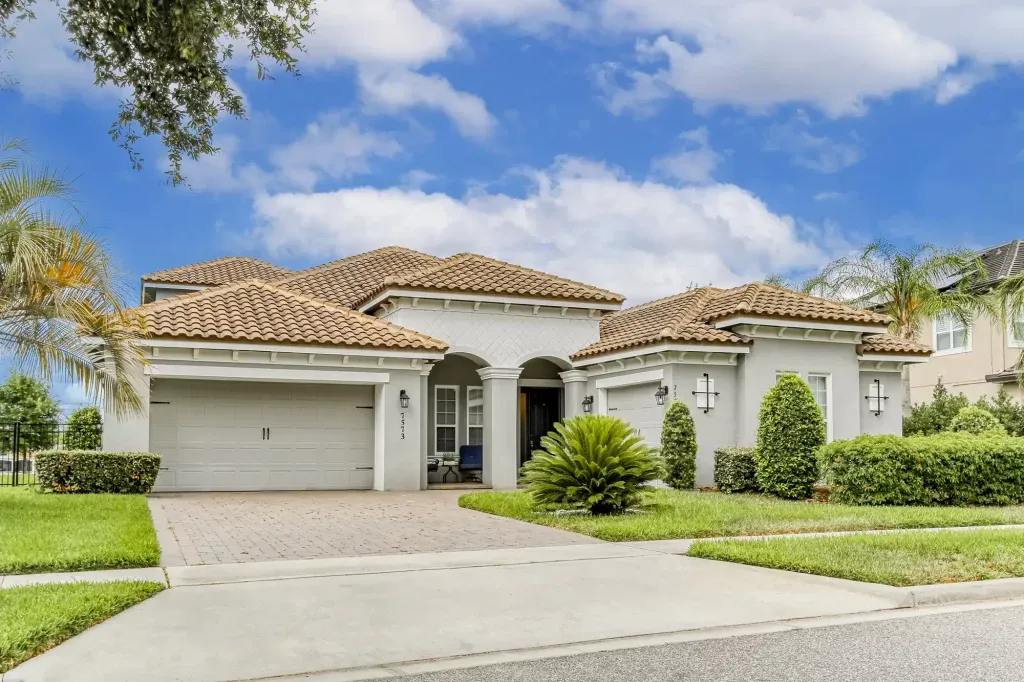 Aerial view of luxury single-story homes with tile roofs and manicured lawns in an upscale Florida neighborhood.