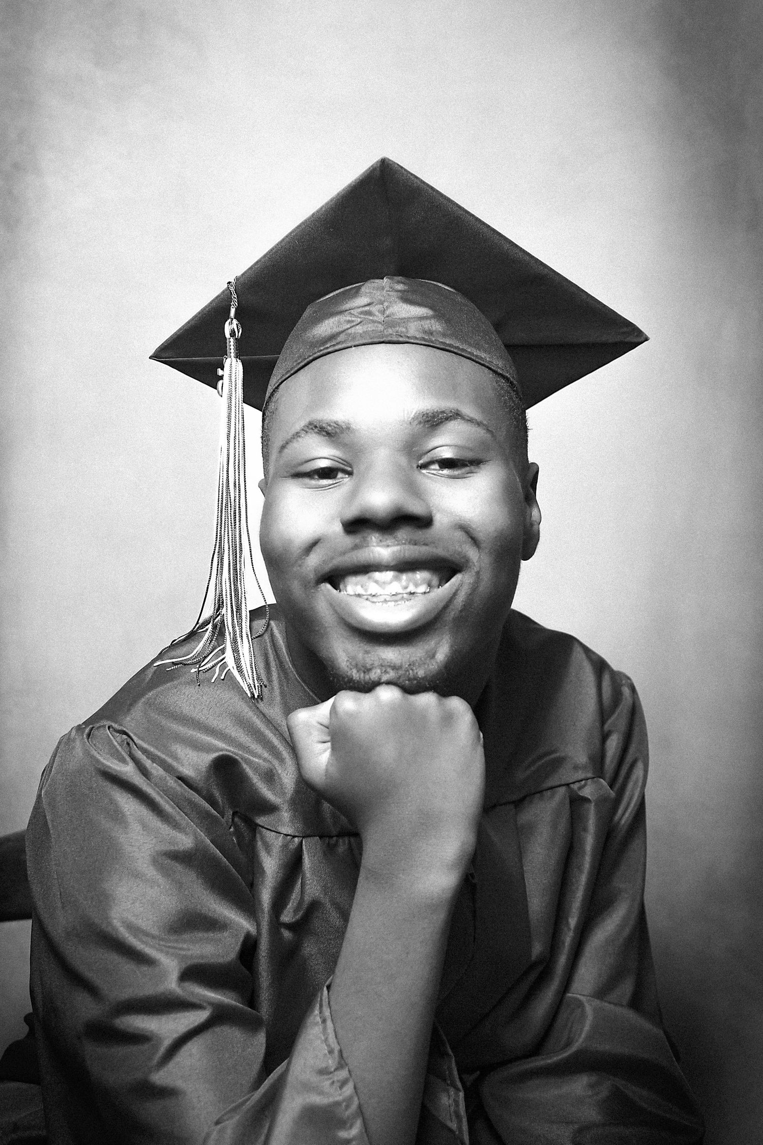 A series of black and white graduation portraits showing joyful expressions in cap and gown.