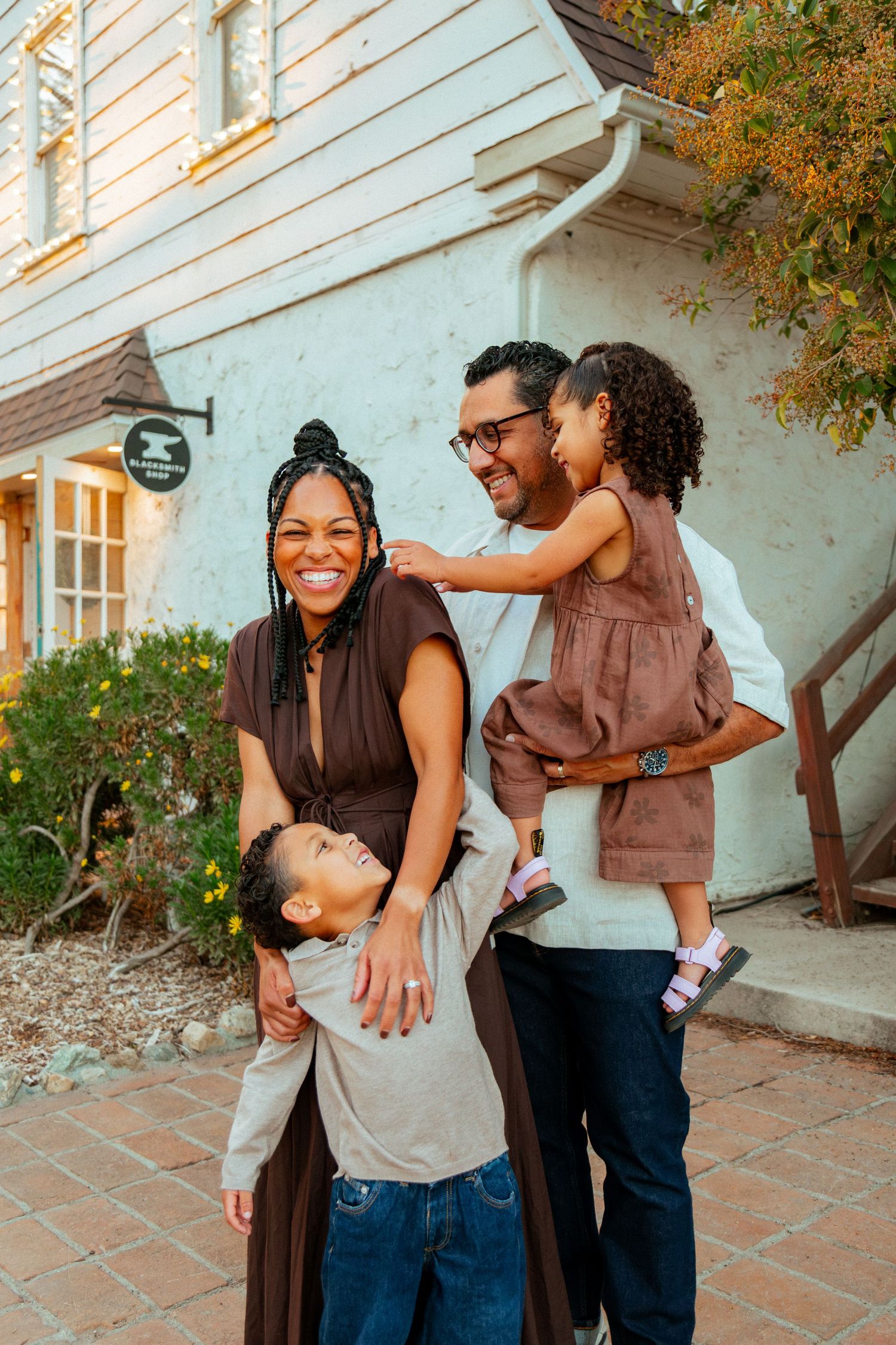A family shares joyful moments together on a brick patio with autumn foliage in the background.