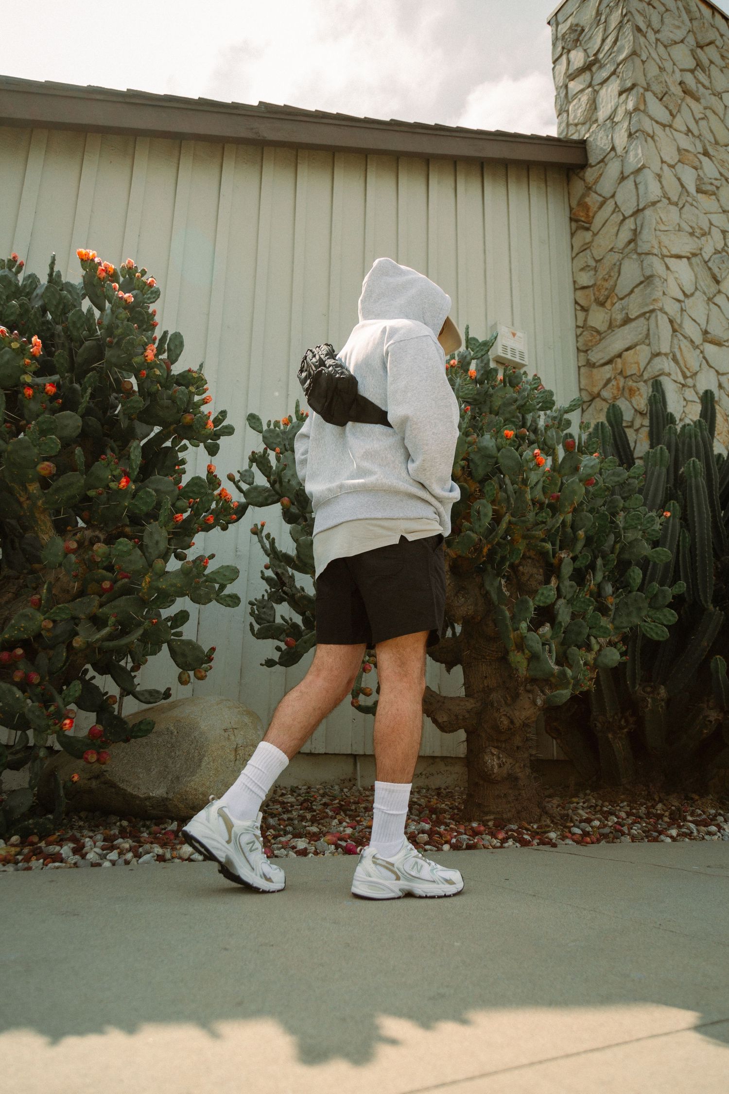 A series of four photos showing white socks and sneakers with shorts against a beige wall and flowering bushes.