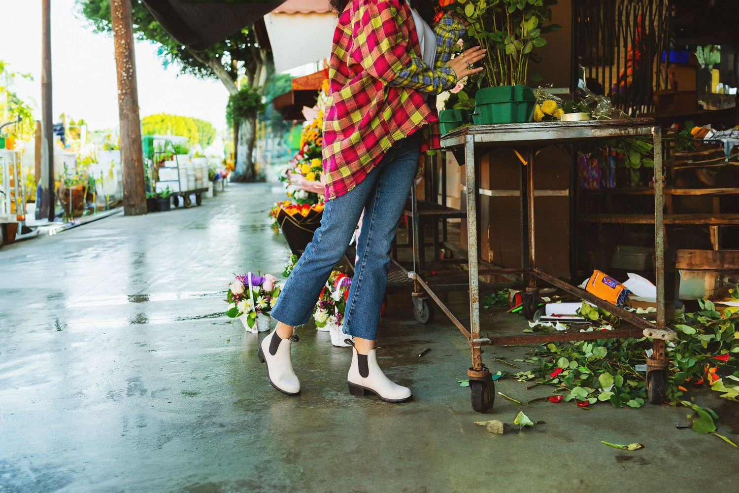 Legs in white boots and red plaid skirt shown in four sequential photos walking across a wet patio area.