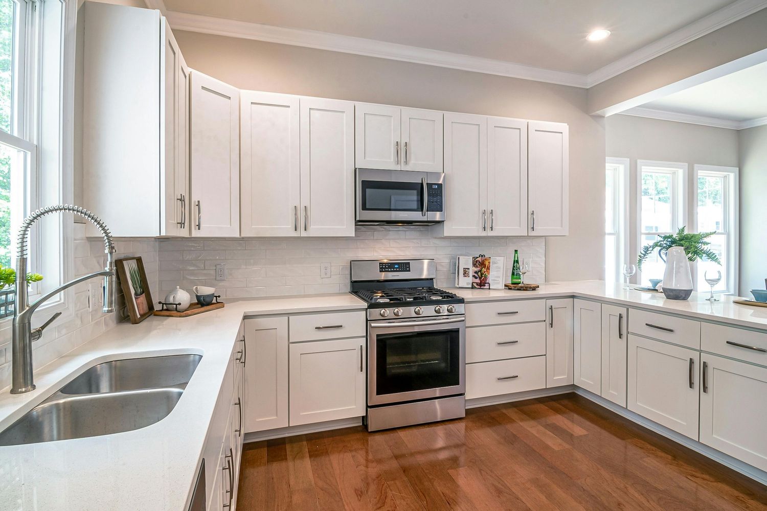 Modern white kitchen with panoramic view showing shaker cabinets, stainless appliances and recessed lighting.