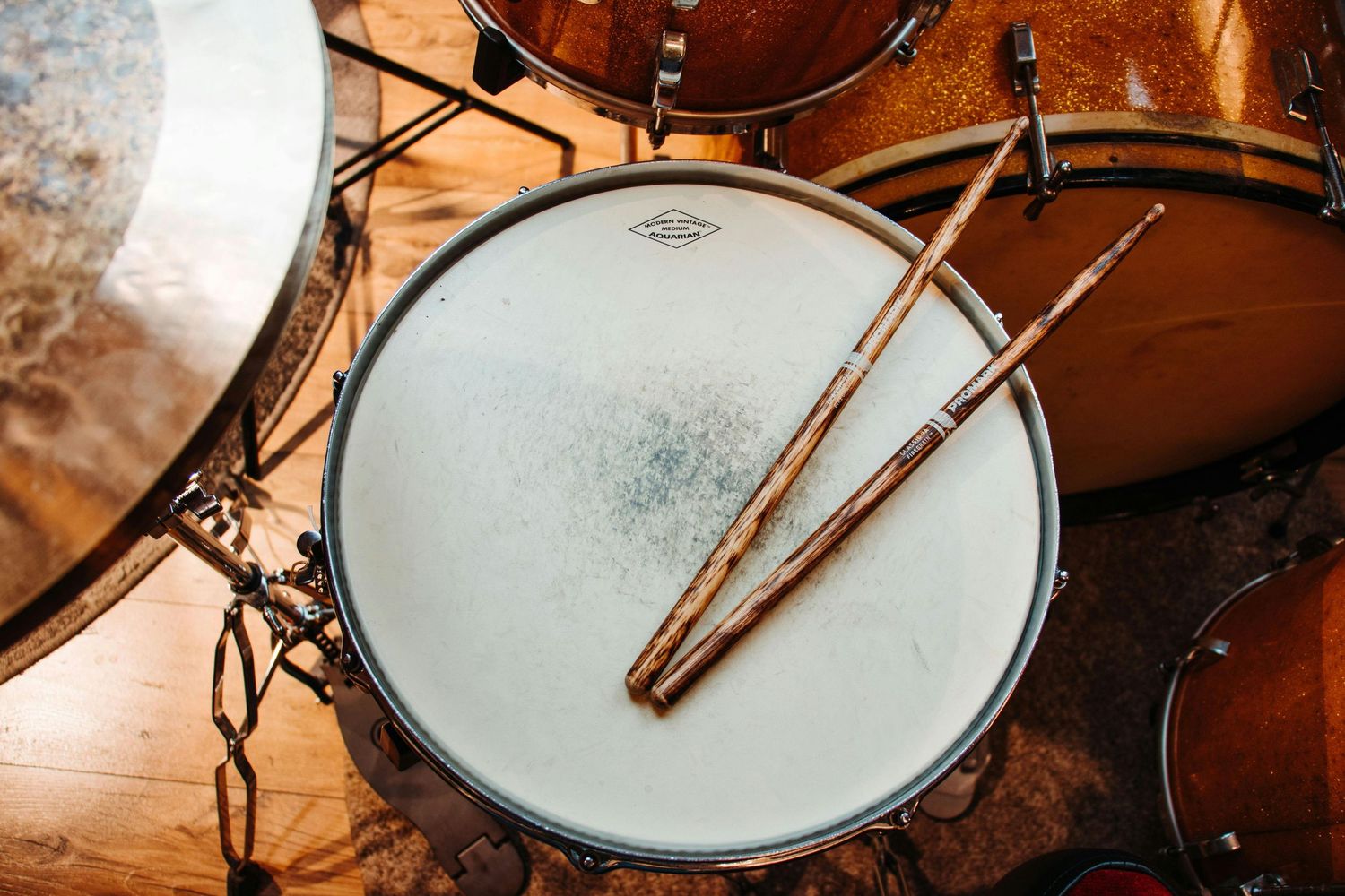 A row of snare drums with silver hardware and wooden rims captured from various angles in warm lighting.