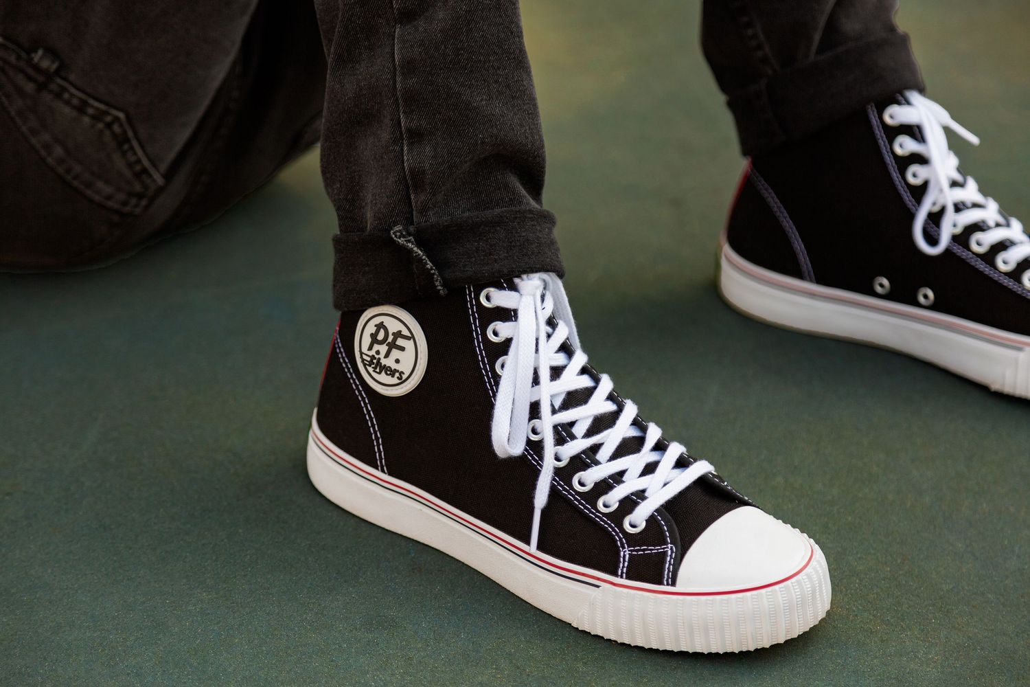 Close-up sequence showing black and white canvas sneakers with white laces against a dark background.