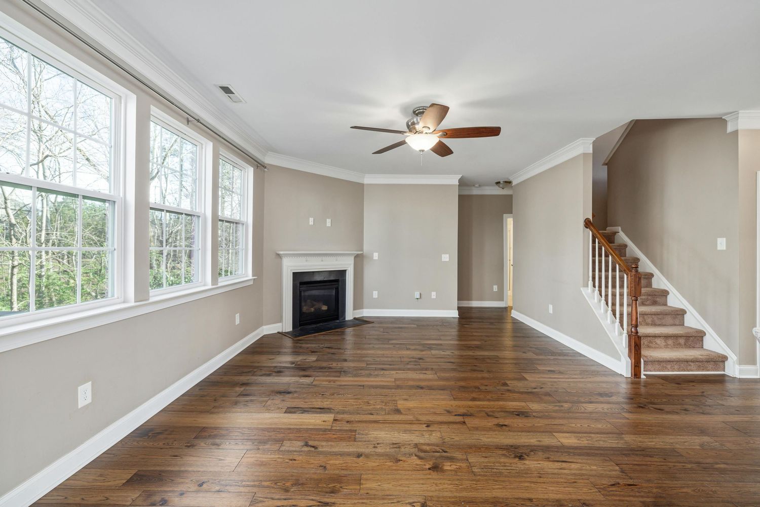 Bright modern living room with hardwood floors, white walls, and large windows showcasing natural light.