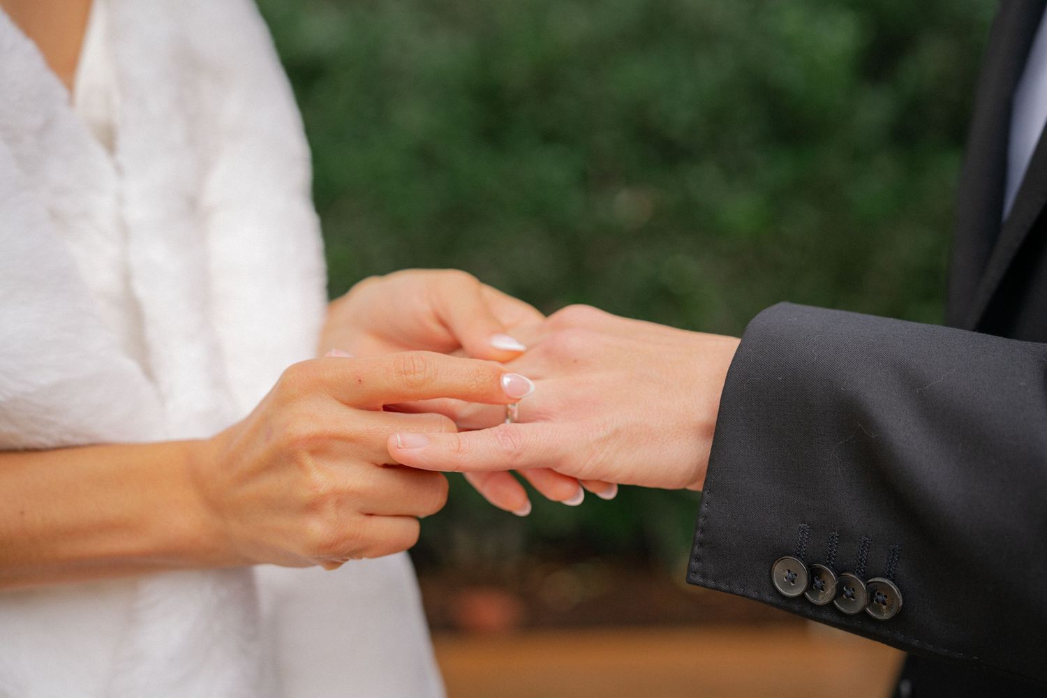 A close-up sequence of hands exchanging wedding rings during a marriage ceremony.