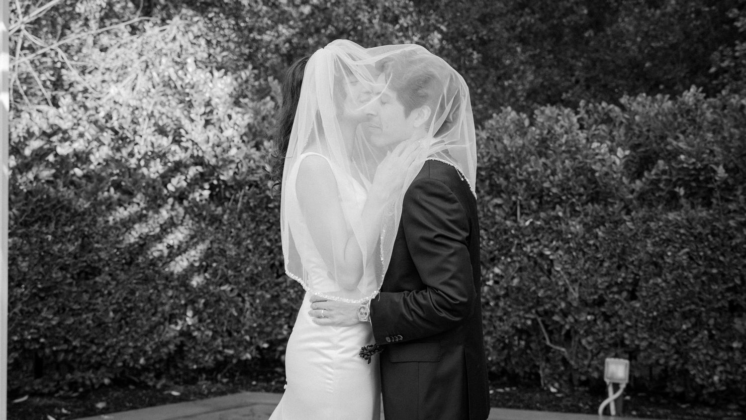 A romantic black and white wedding photo collage showing intimate moments between newlyweds in an outdoor garden setting.
