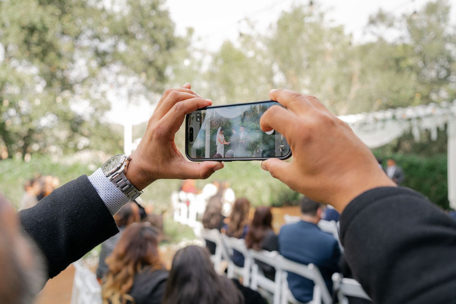Multiple hands hold smartphones to capture photos at an outdoor event or gathering.