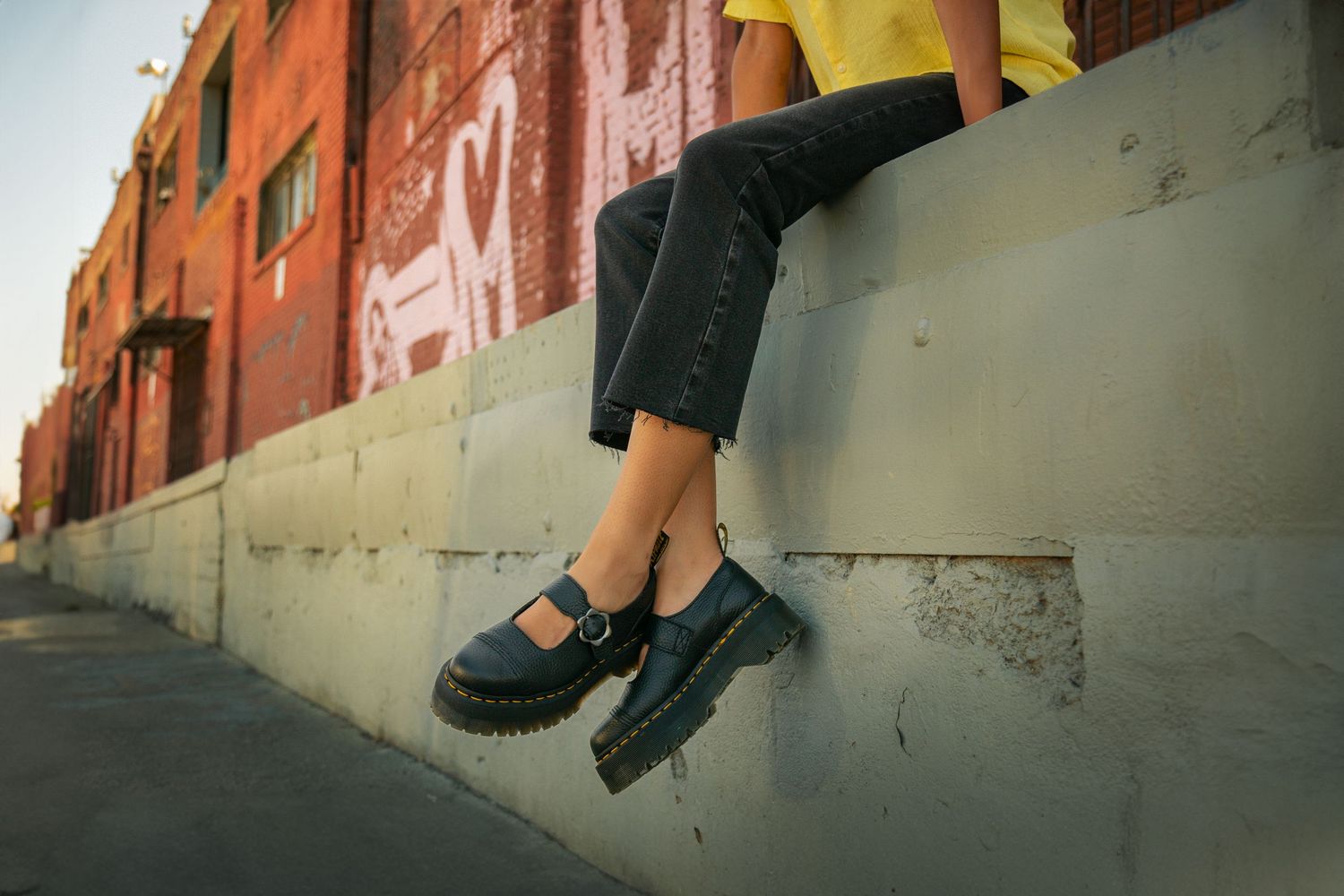 Black dress shoes and dress pants are shown walking on a textured concrete surface.