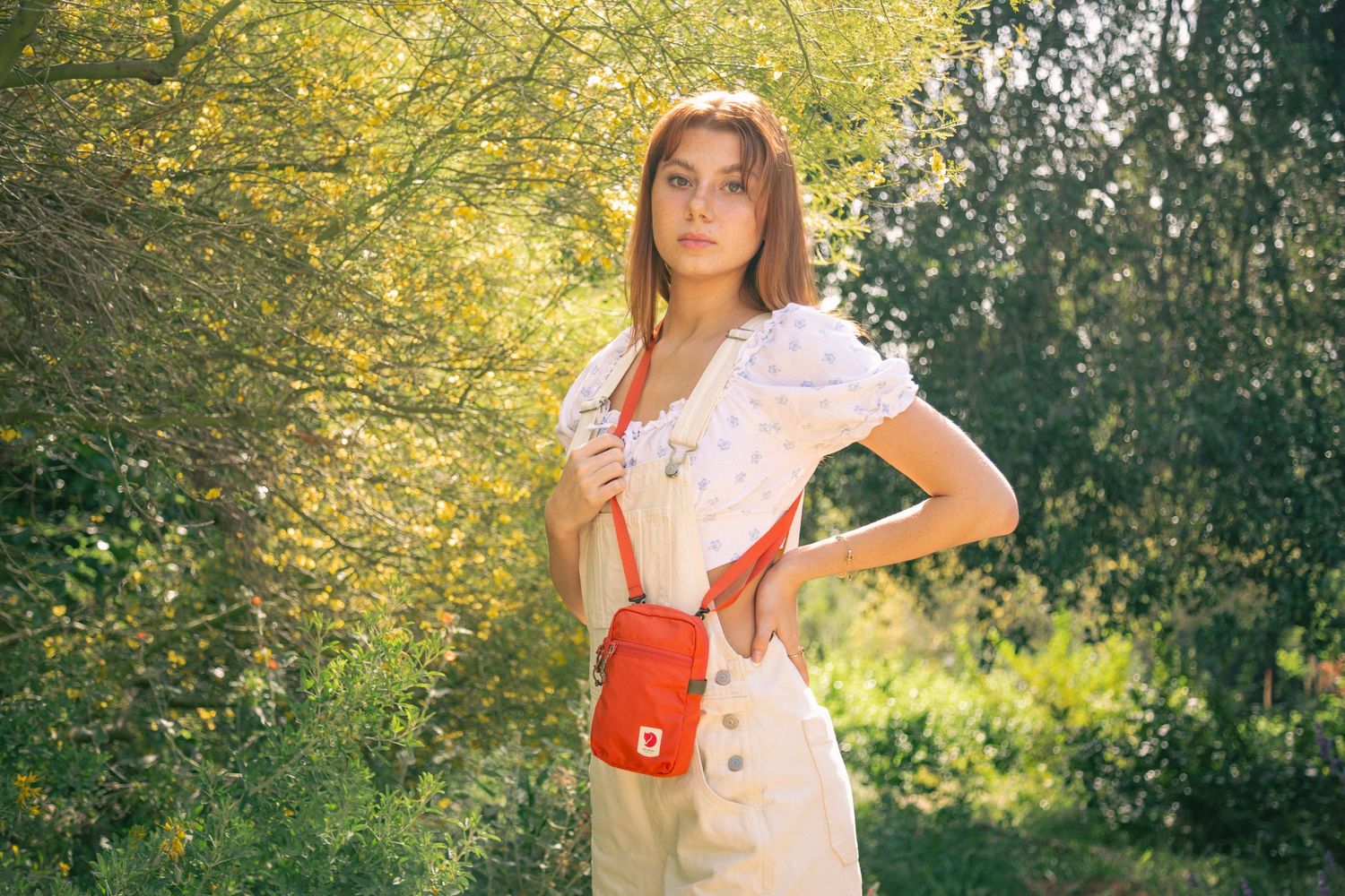 A person in a flowy pink dress twirls playfully in a sunlit garden with golden afternoon light filtering through trees.
